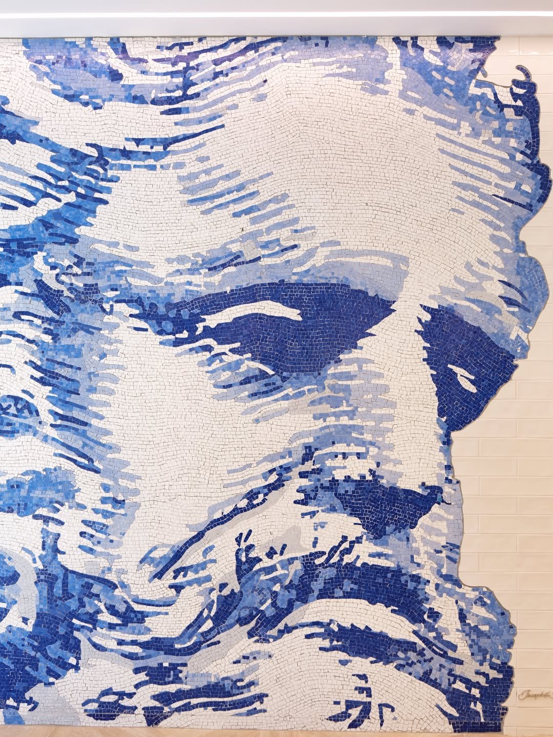 Close-up of a colorful mosaic depicting a Neptune's face with sunglasses, using shades of blue and white tiles.