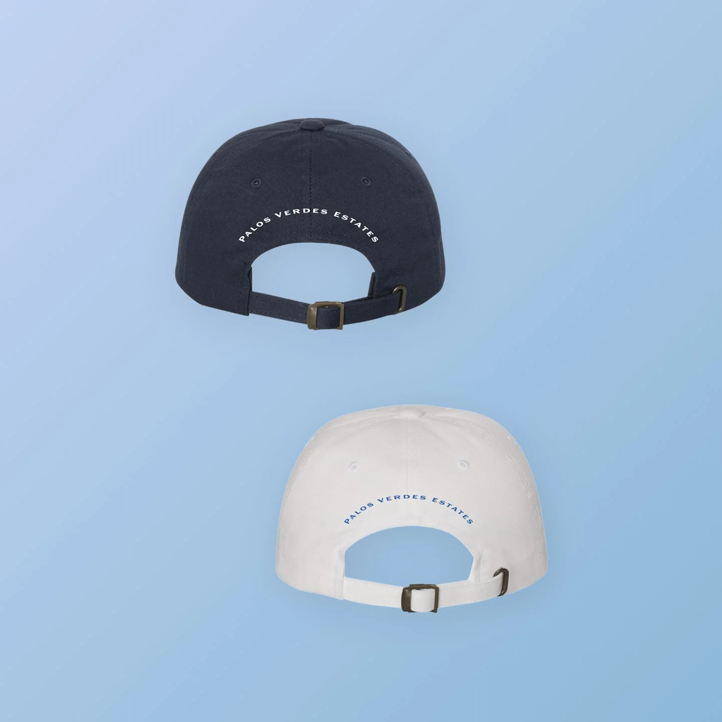 Two baseball caps, one black and one white, with the text 'Palo Verde Estates' embroidered on the back, floating against a light blue background.