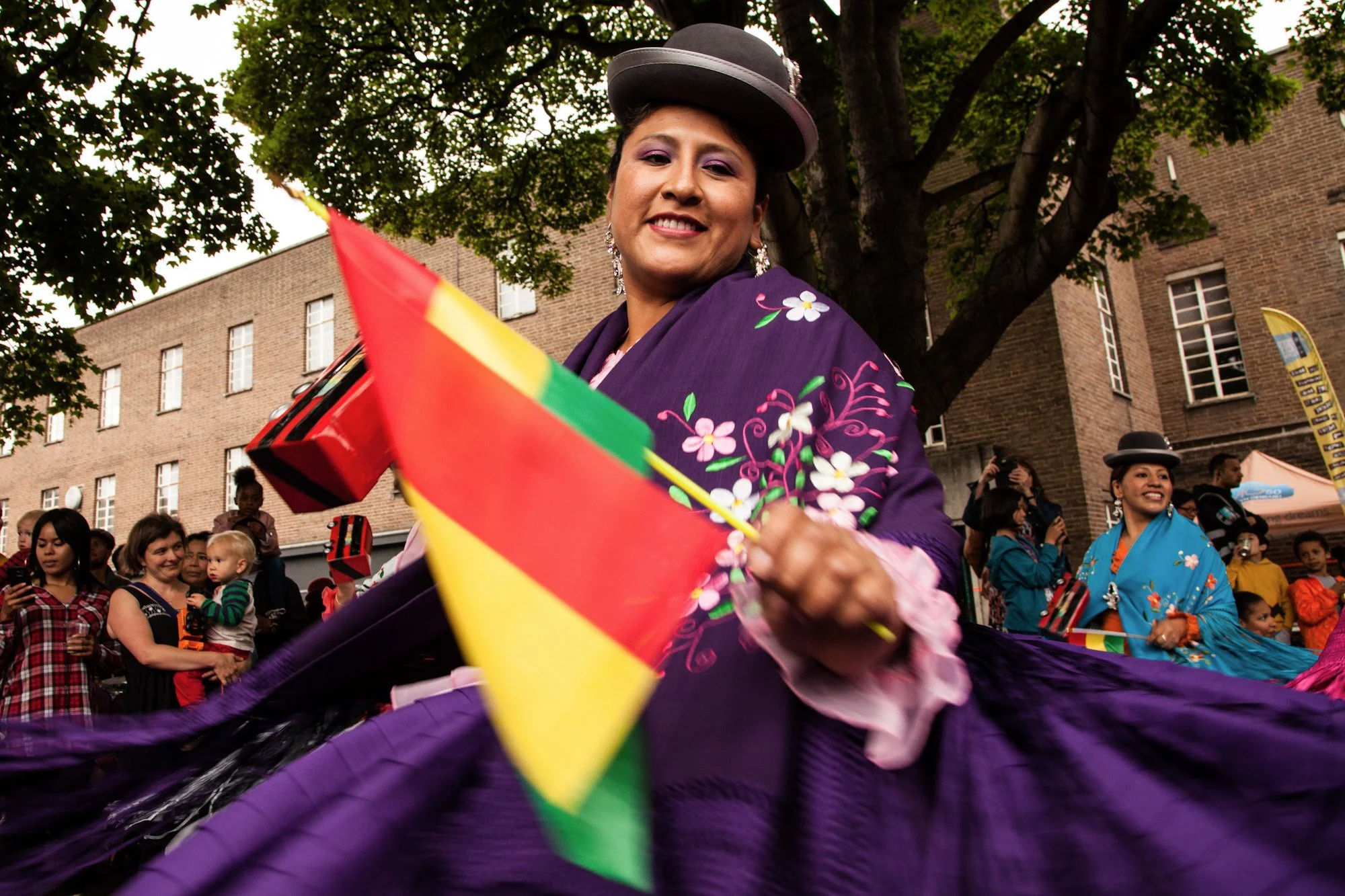 A dancer twirling a purple skirt and rainbow flag in the La Clave festival parade.
