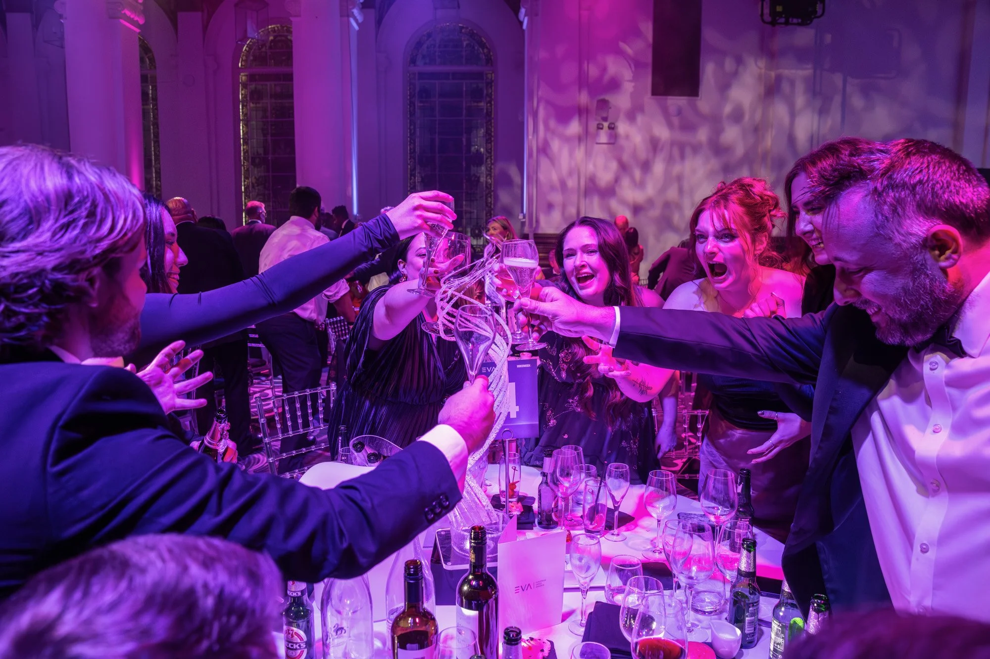 Guests raising their glasses for a toast around a banquet table.