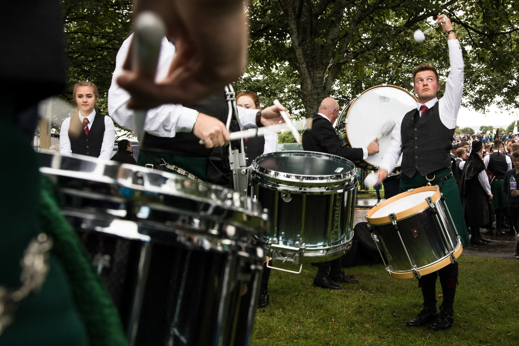 A drum corps performing outdoors in tartan kilts at a pipe-band competition.