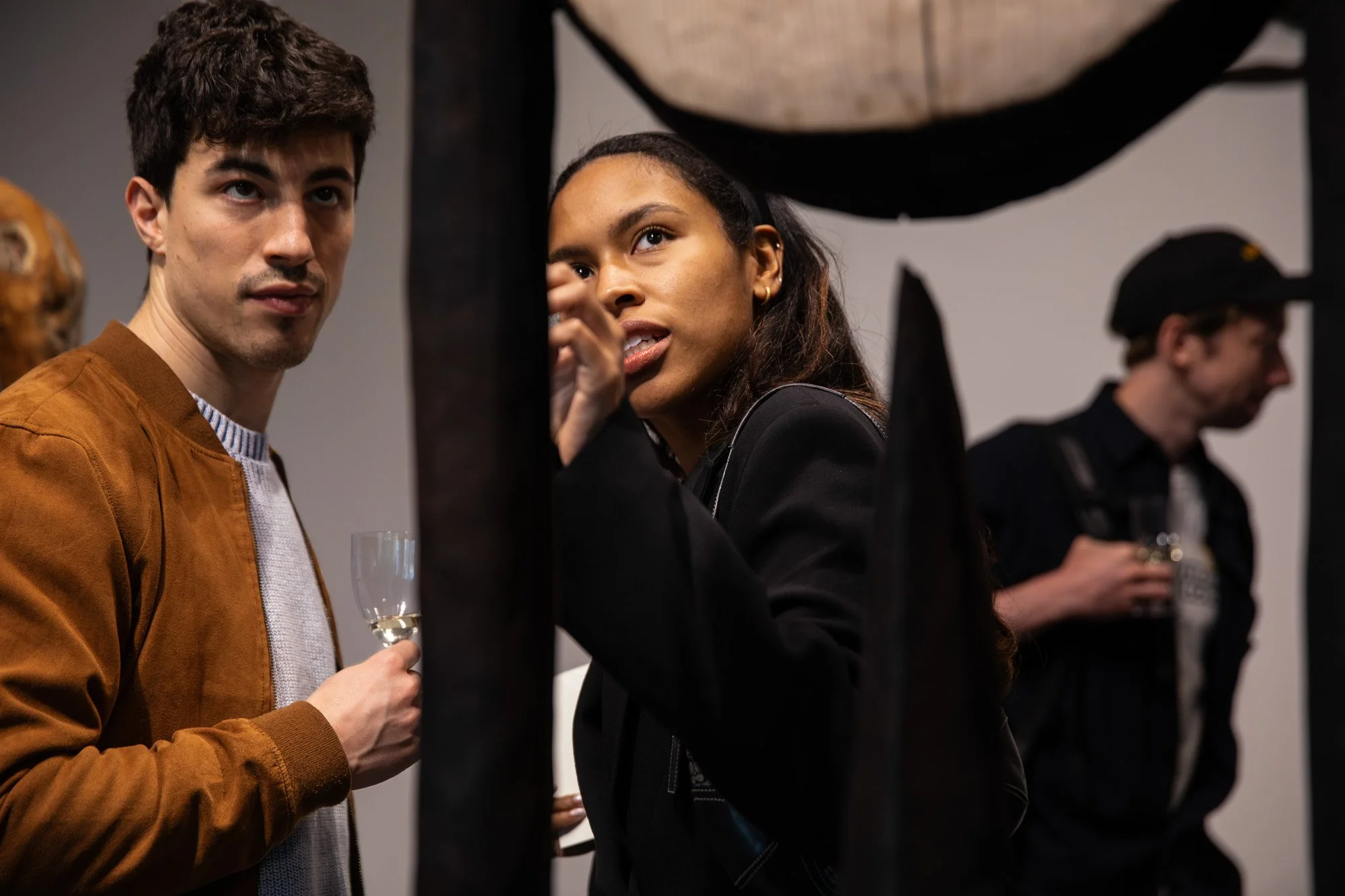 Two guests talking over drinks during a Sol Bailey Barker exhibition reception.