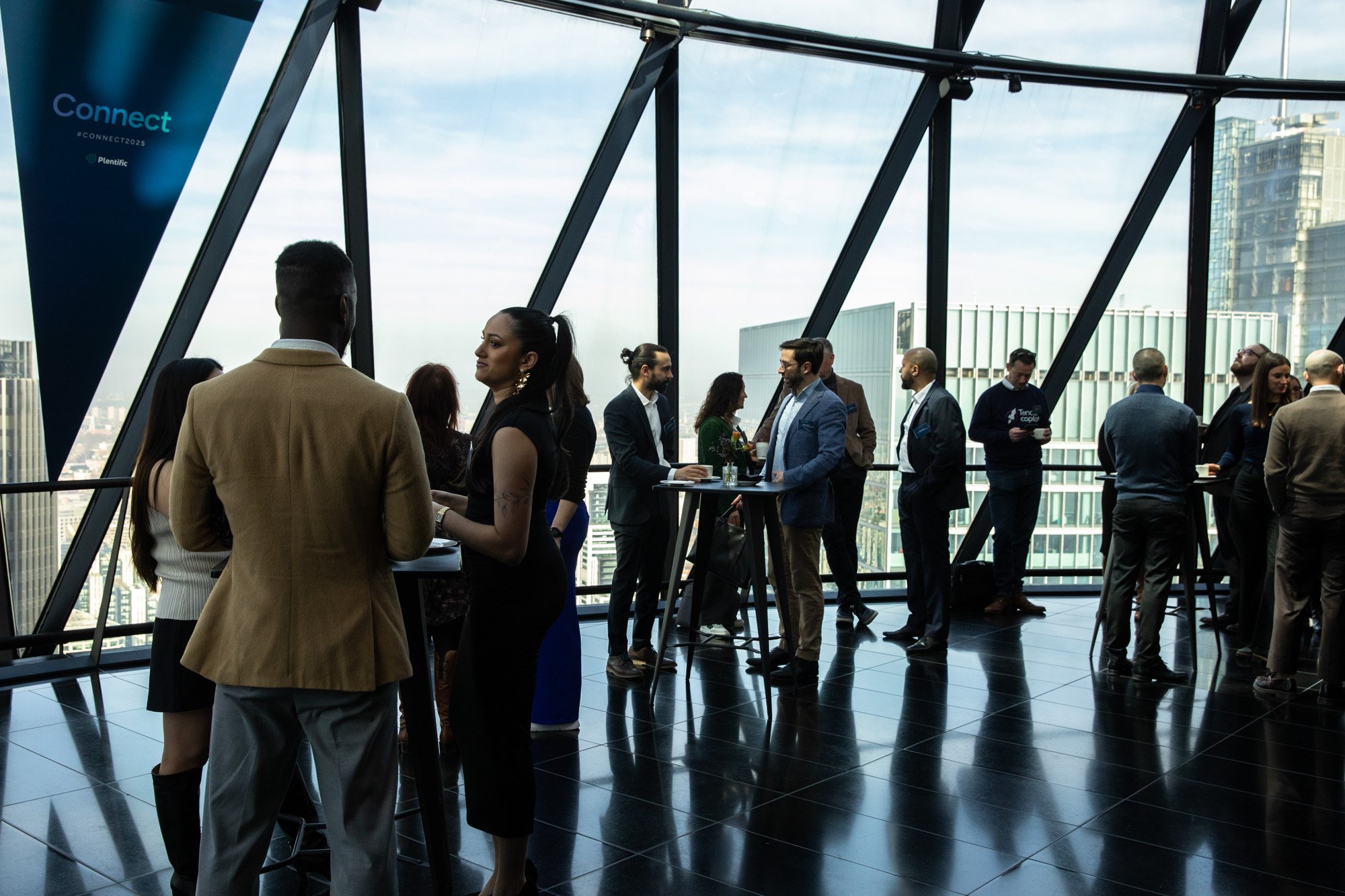 Delegates talking beside floor-to-ceiling windows overlooking the city.