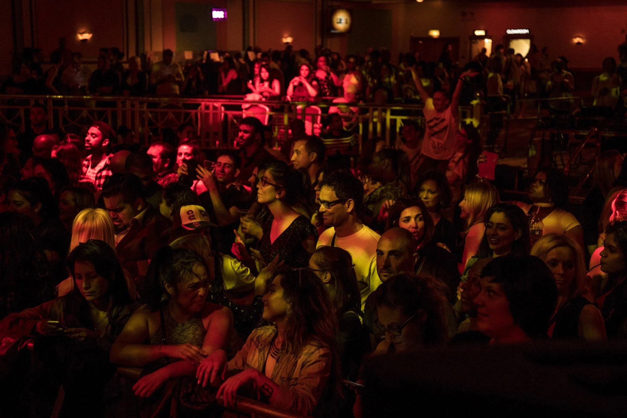 An audience watching an awards ceremony under red and yellow lighting.