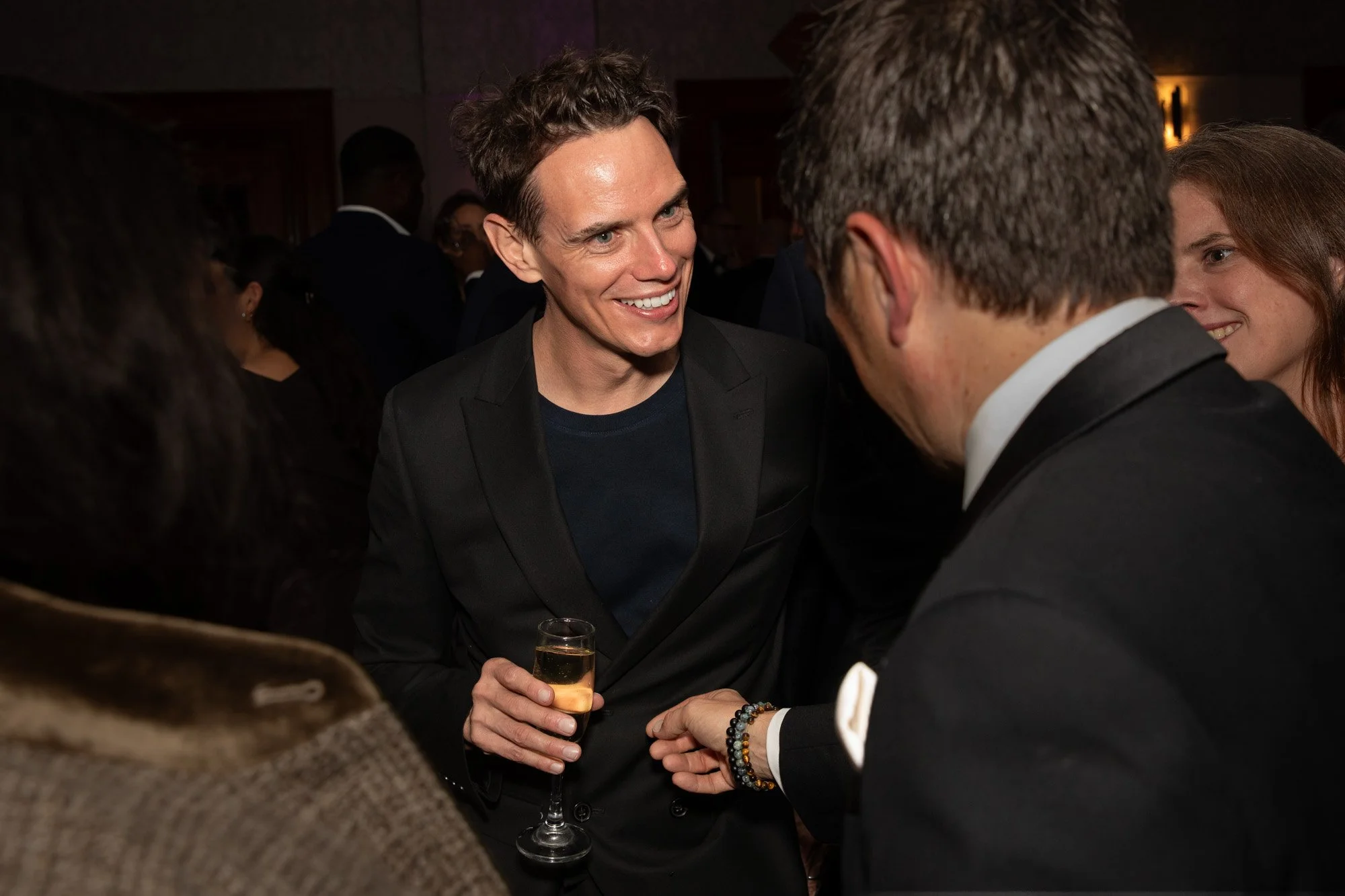 Two guests smiling and talking with drinks at an awards reception.