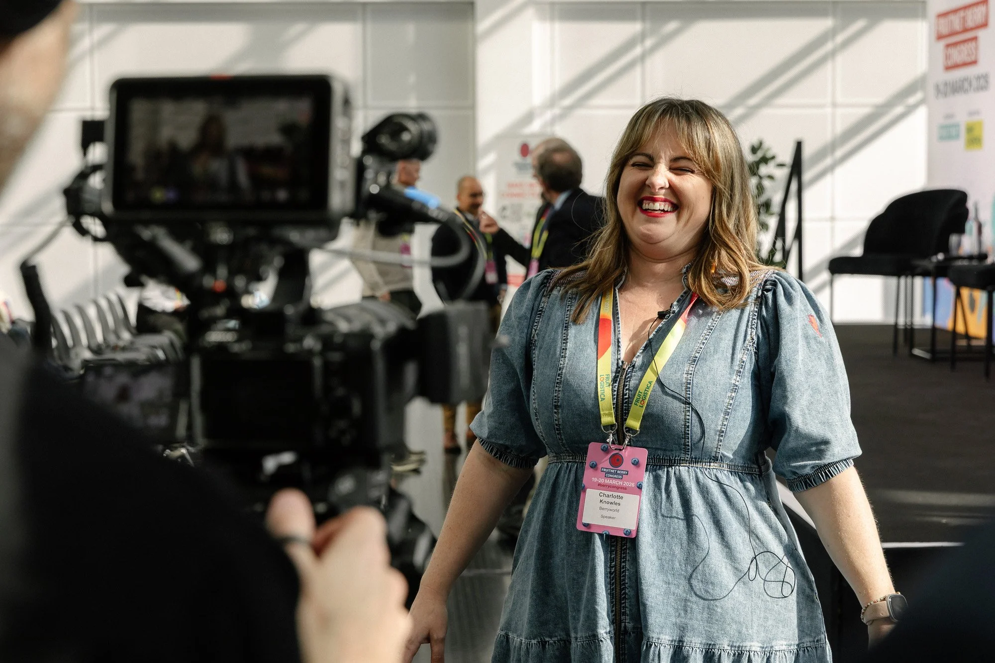 Behind the scenes of a filmed interview with a conference attendee wearing an event lanyard.