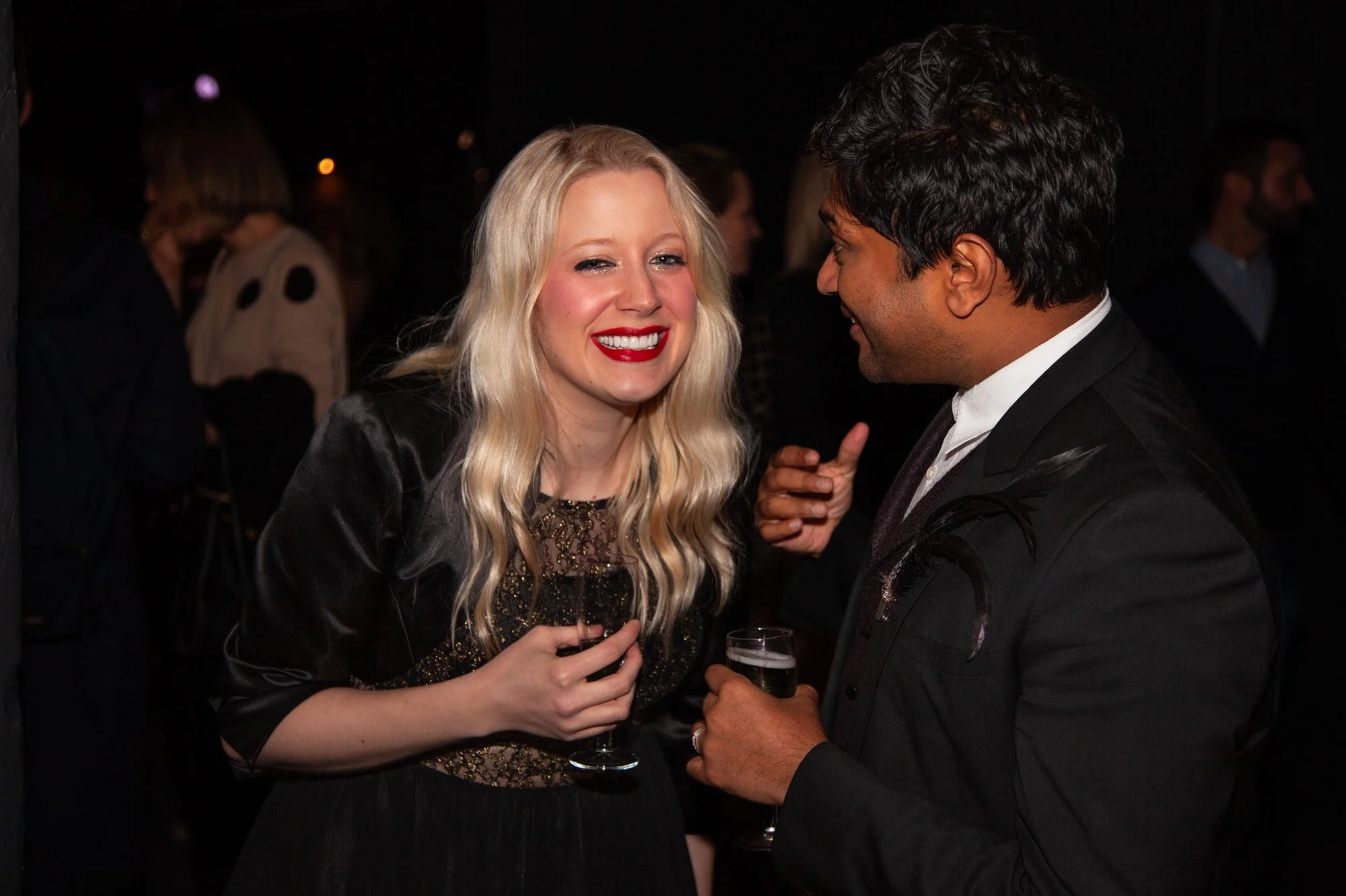 Two guests laughing together with drinks at an awards reception.