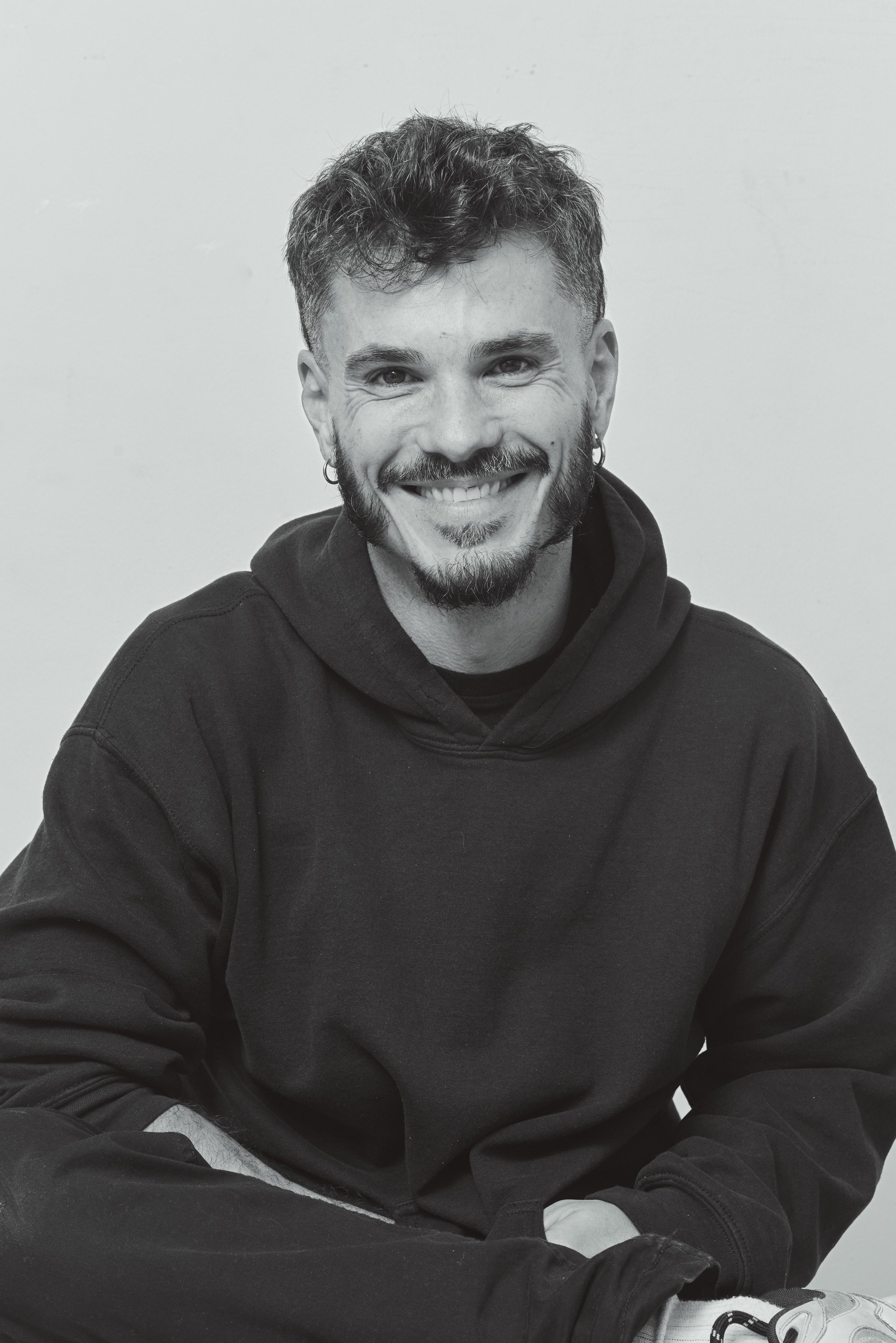 Black-and-white portrait of Manu Valcarce, founder of MVV Media, smiling at the camera.