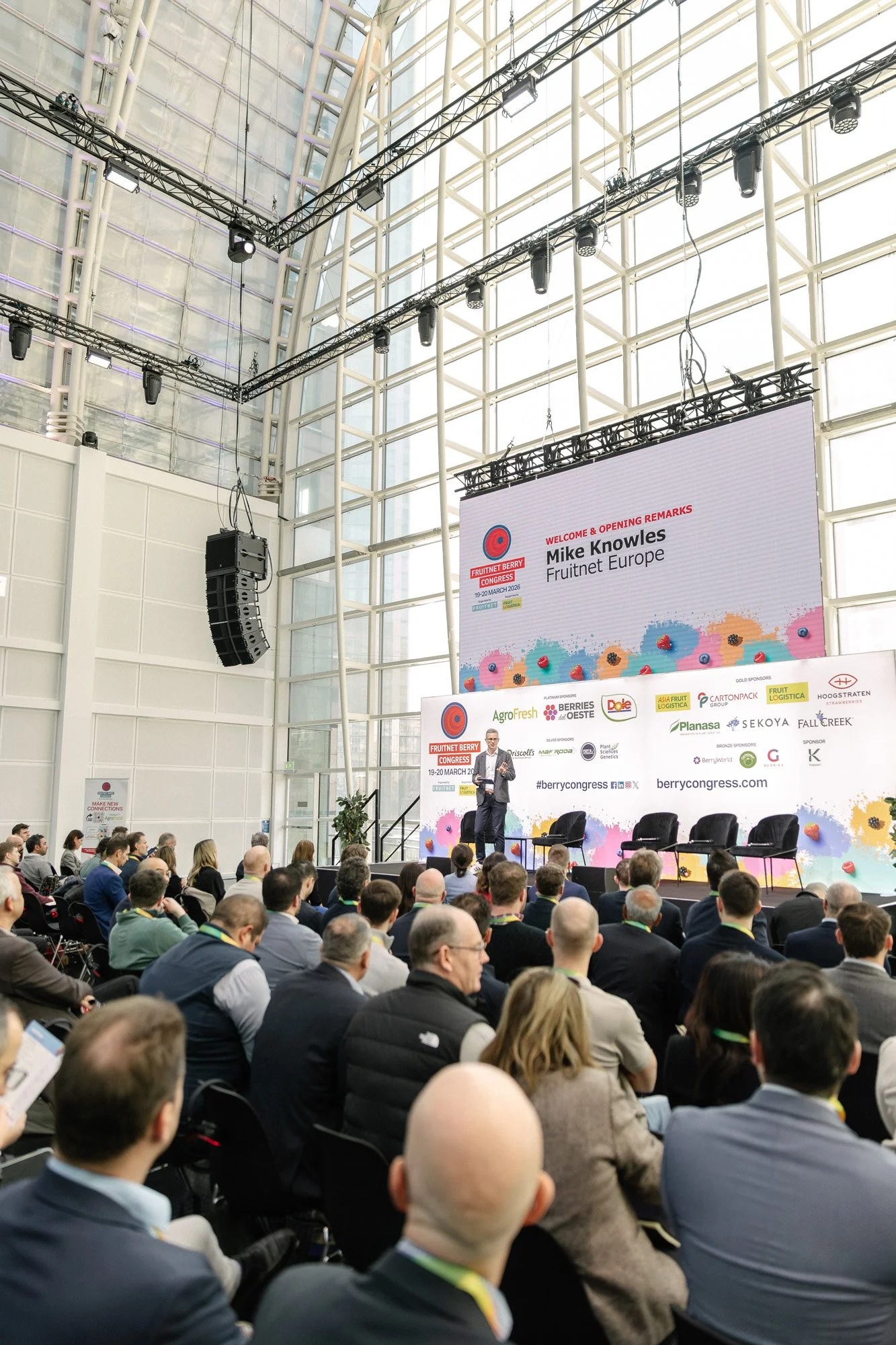 A speaker presenting to seated delegates at Fruitnet Berry Congress in a bright conference hall.