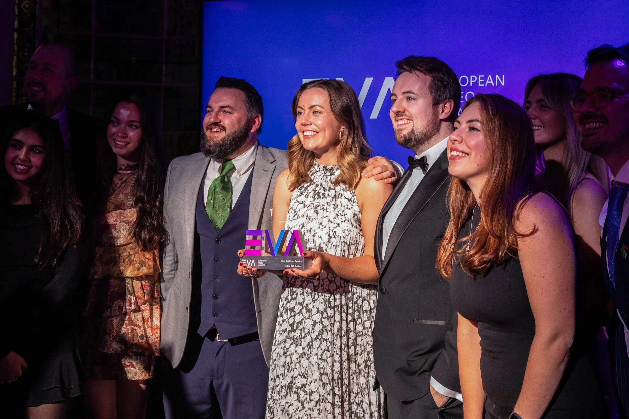 A group posing with a European Video Awards trophy against a blue event backdrop.