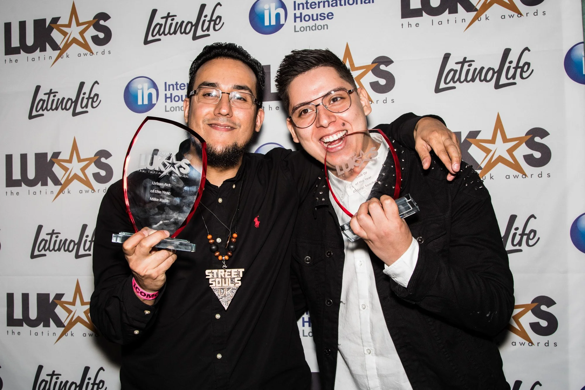 Two smiling guests holding trophies in front of the LUKAS Awards backdrop.