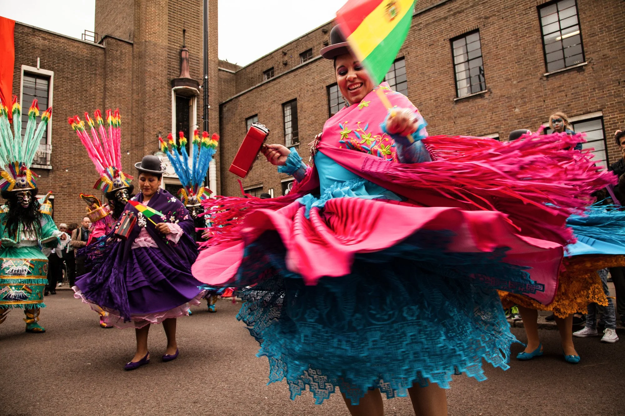 Dancers spinning in bright layered skirts at a LatinoLife street festival.