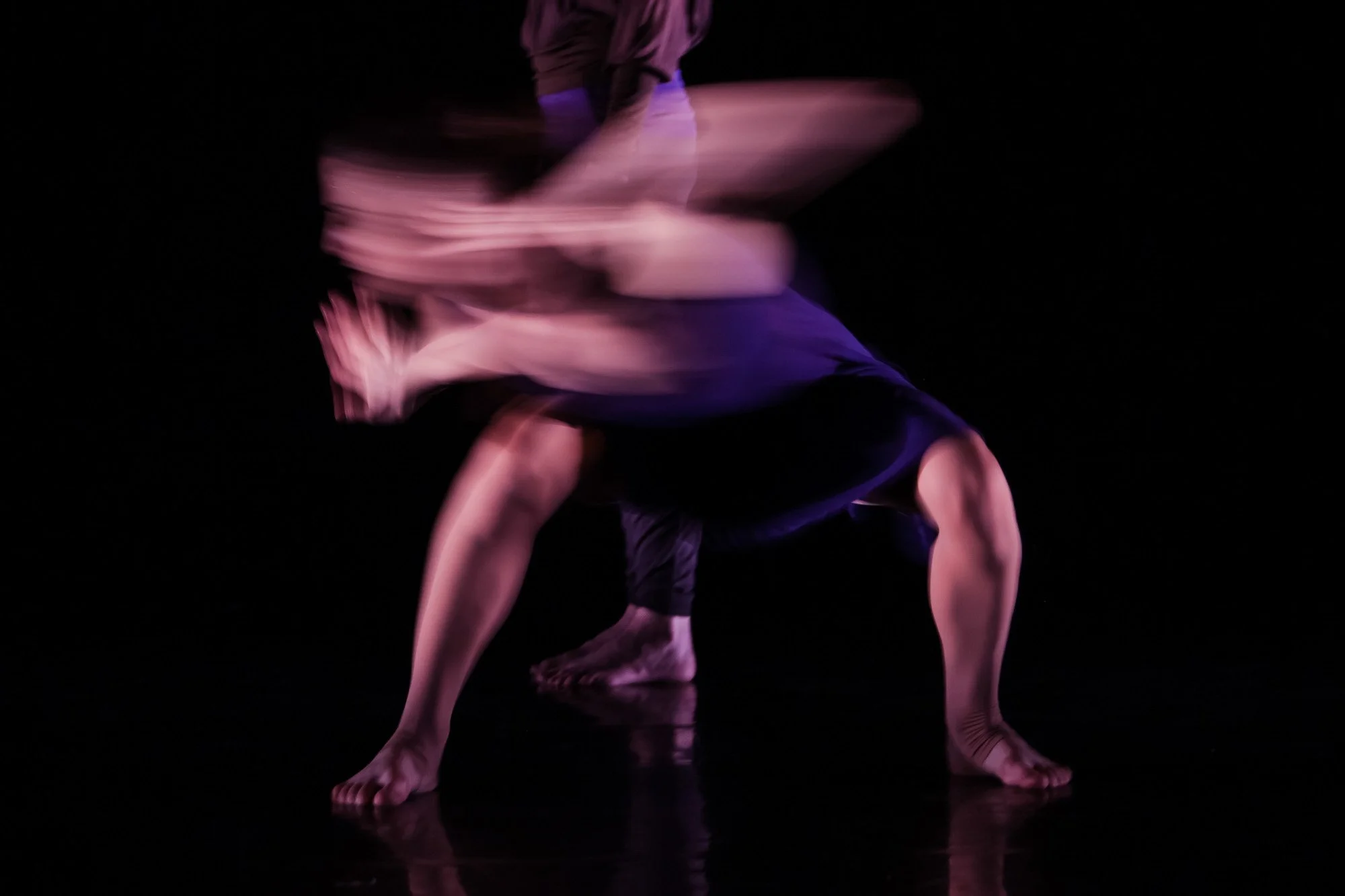 A dancer captured with motion blur against a dark stage background.