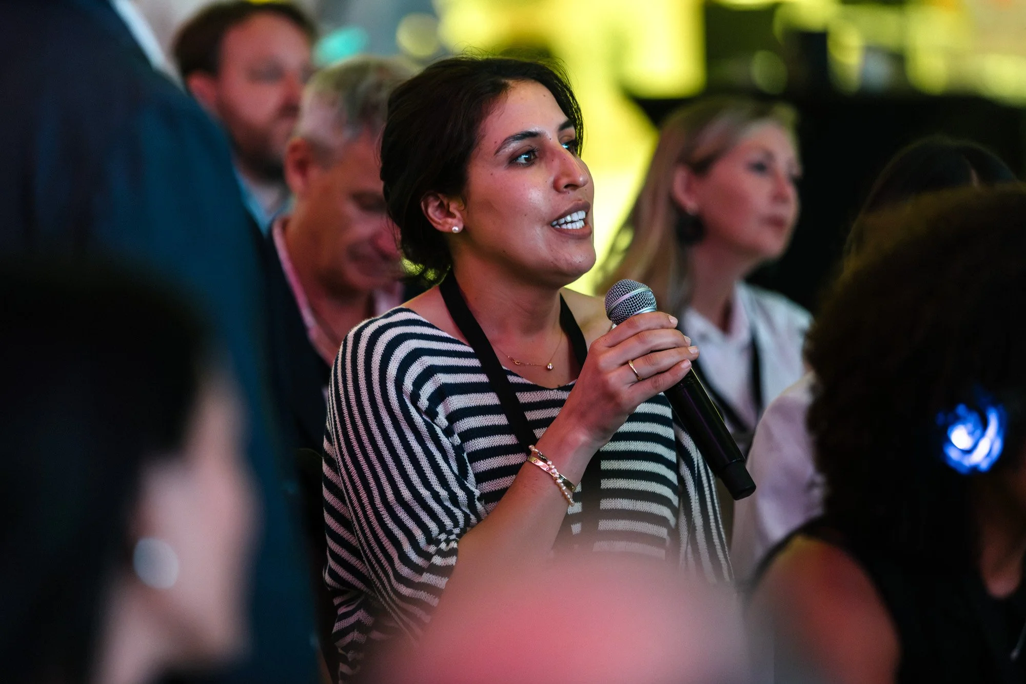 An audience member holding a microphone during a conference discussion.
