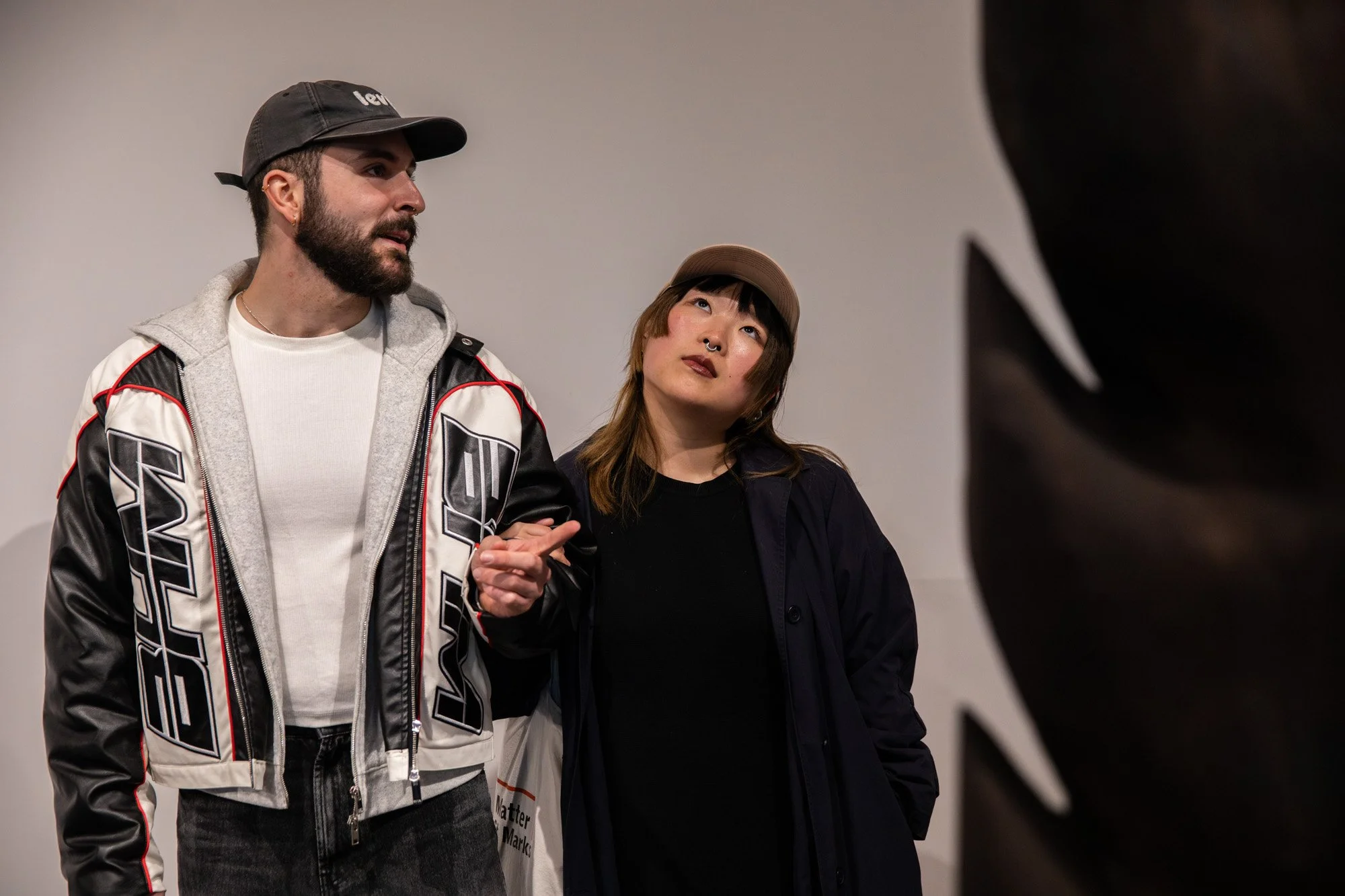 Two visitors looking up at an exhibit during a Sol Bailey Barker gallery event.