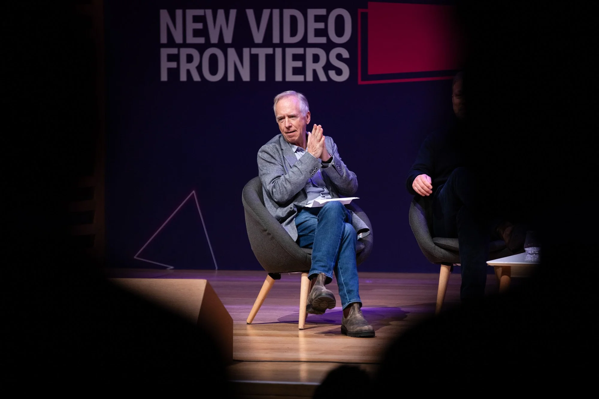 A male panellist seated on the New Video Frontiers stage during a discussion.
