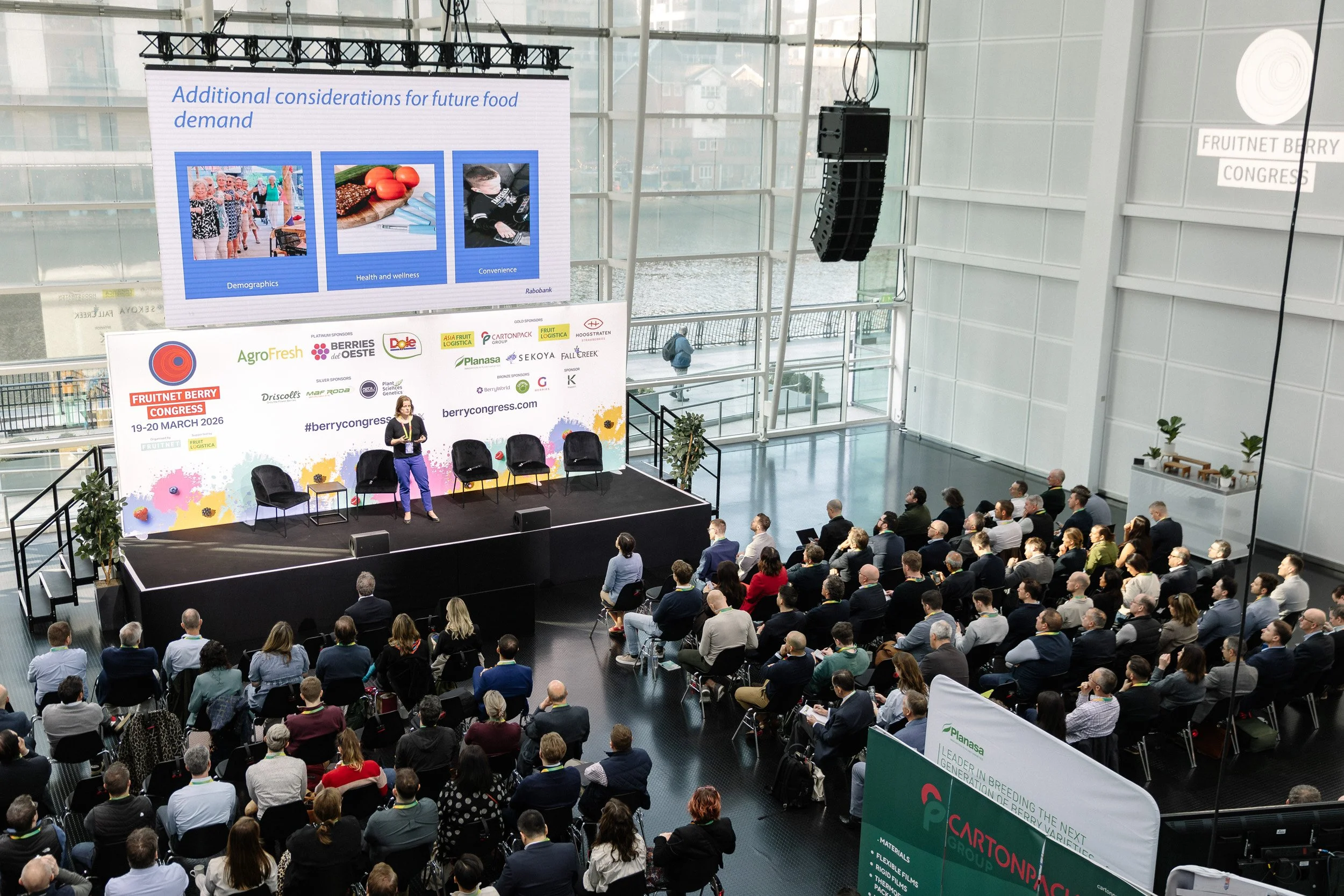 Wide-angle view of a speaker presenting to a large audience at the Fruitnet Berry Congress 2026.