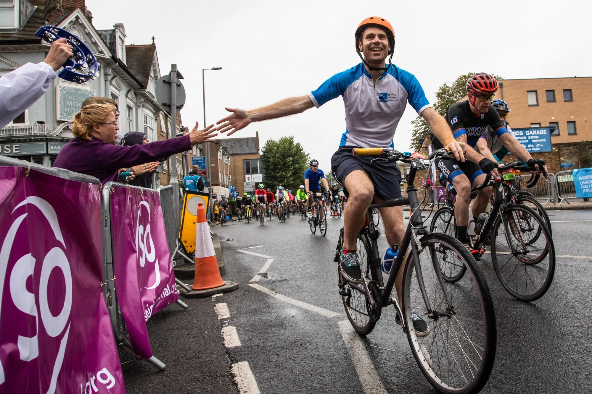 A smiling cyclist reaching out to high-five a VSO supporter during RideLondon.