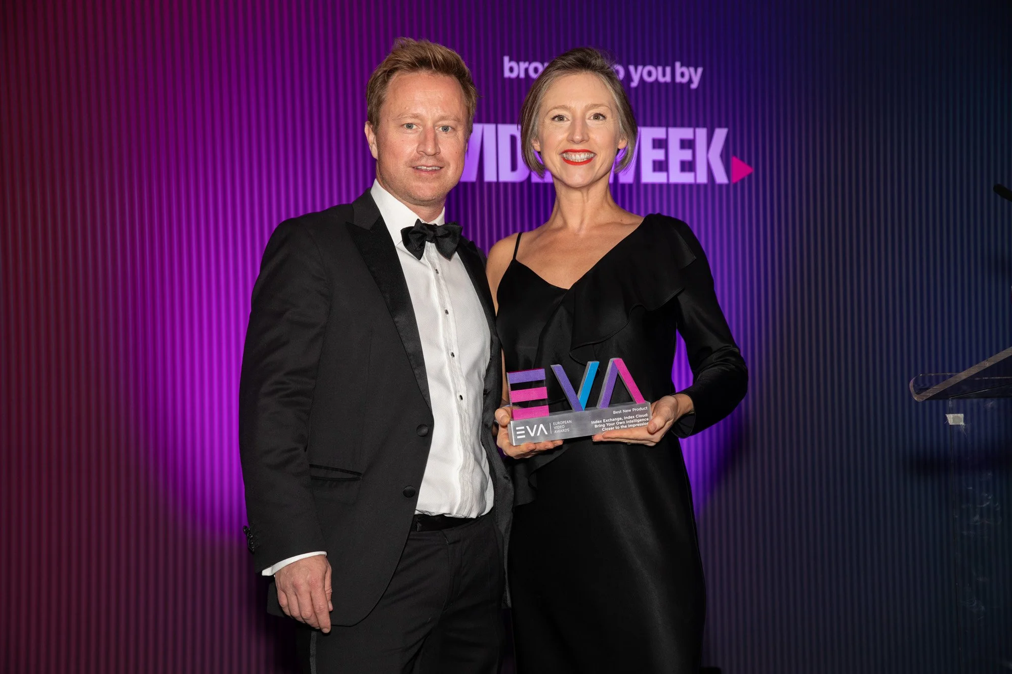 Two guests posing with a European Video Awards trophy in front of the event backdrop.