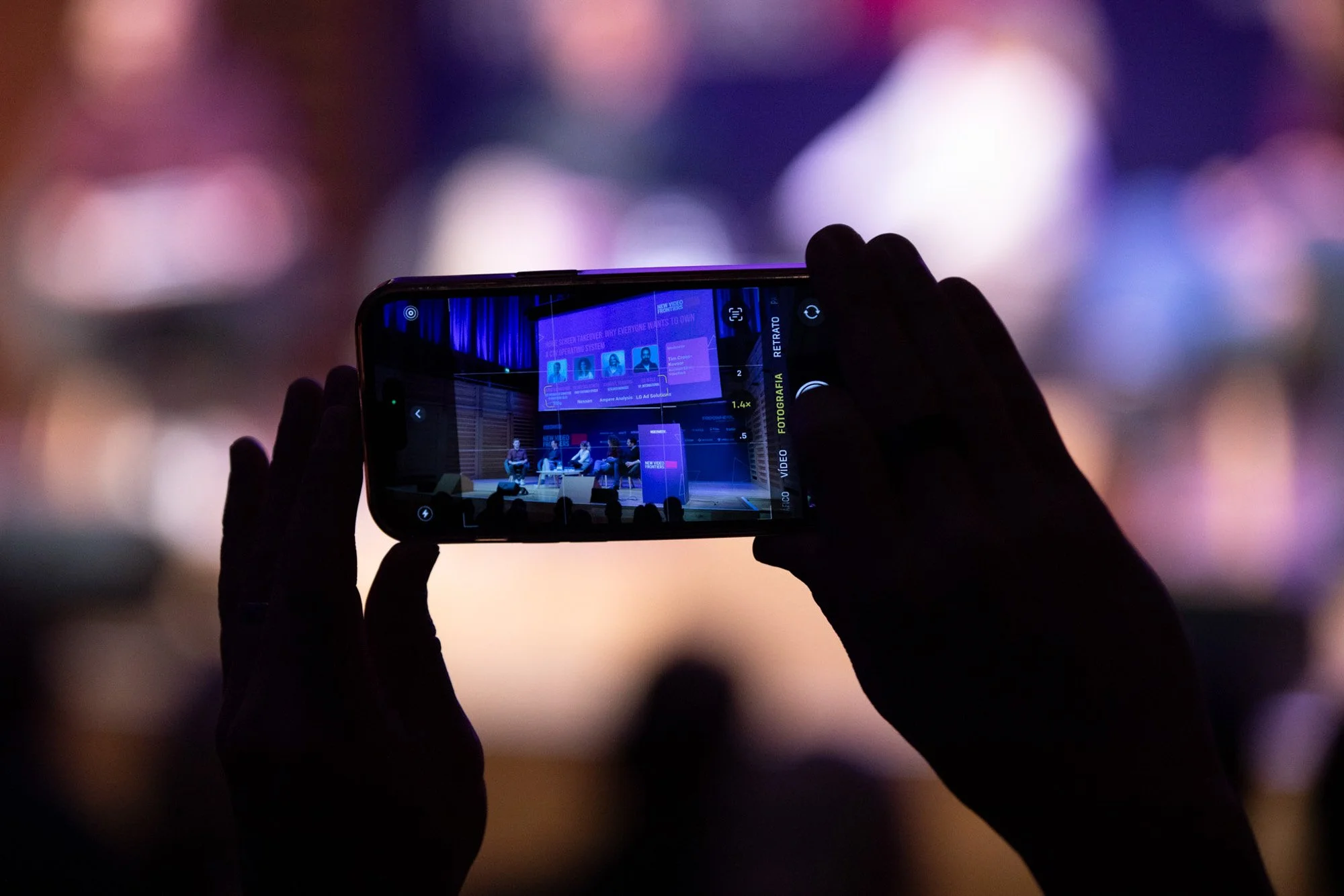 An attendee photographing a conference presentation with a smartphone.