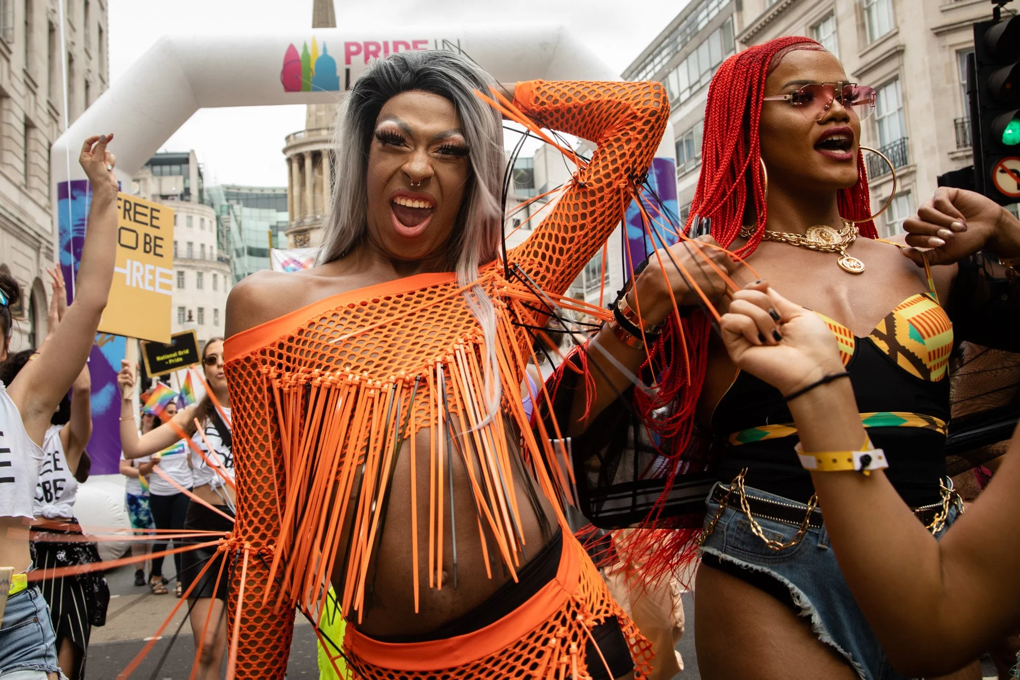 Pride participants in colourful outfits cheering together during the parade.