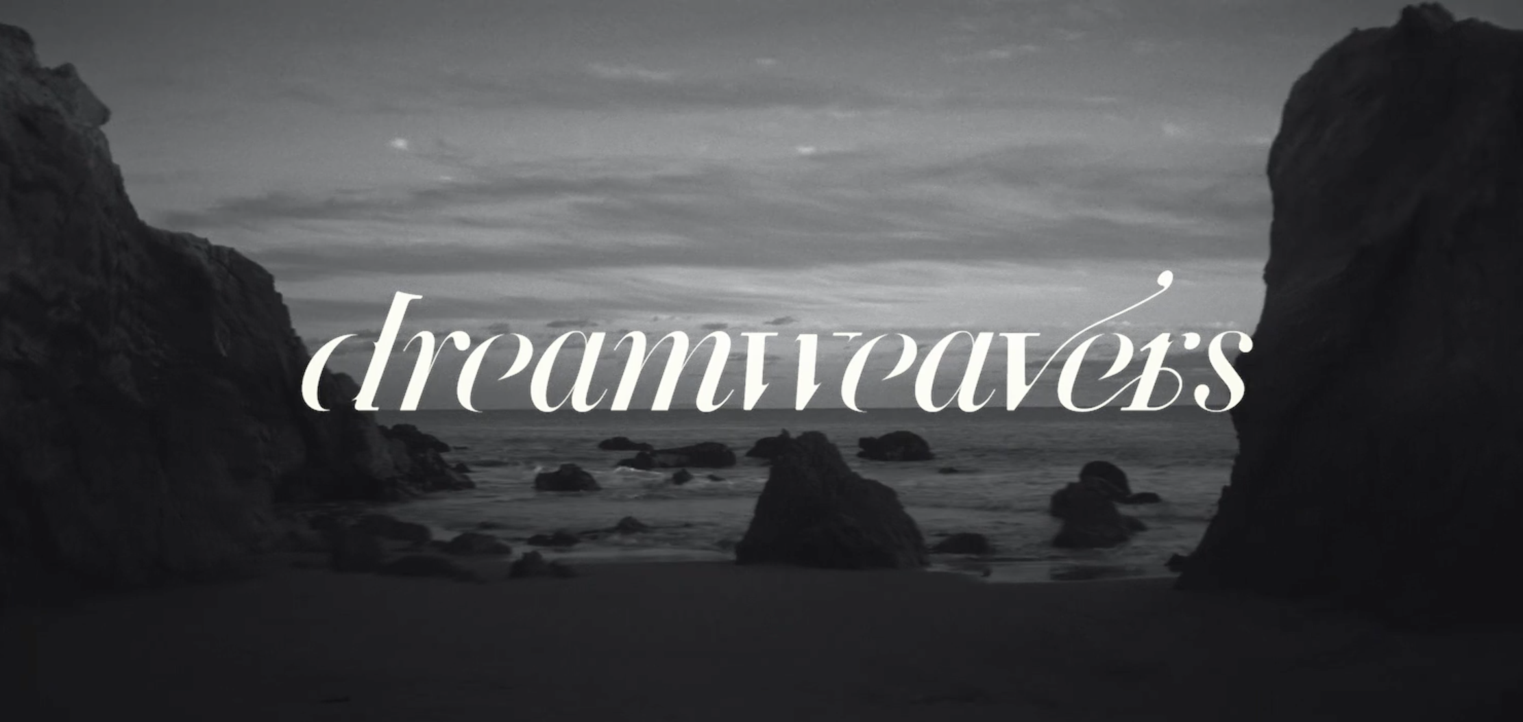Black and white photo of a rocky coastline with the ocean and clouds, overlaid with the word 'dreamtapes' in elegant cursive font.