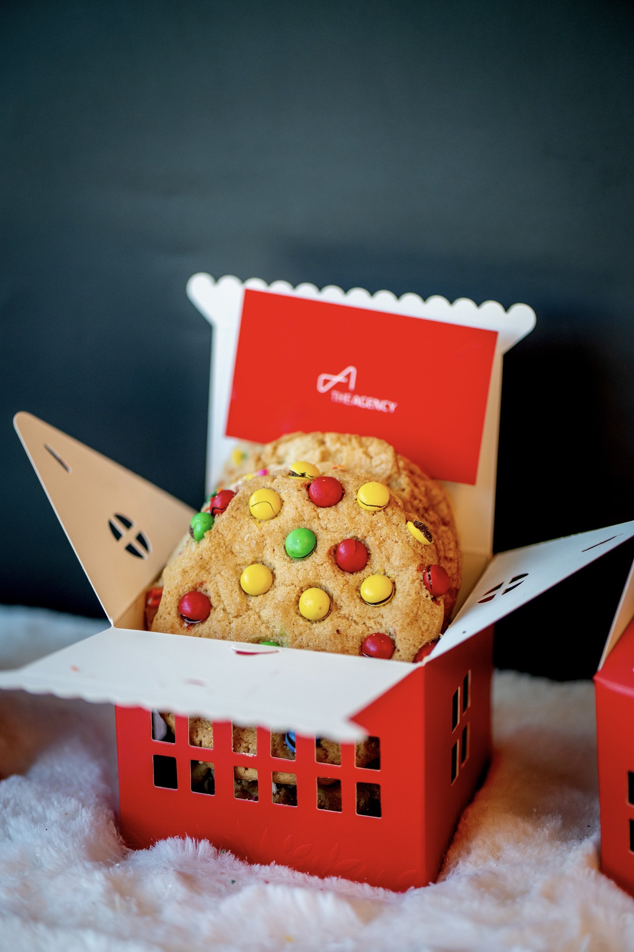 Stacks of assorted cookies and brownies beside a silver gift box.