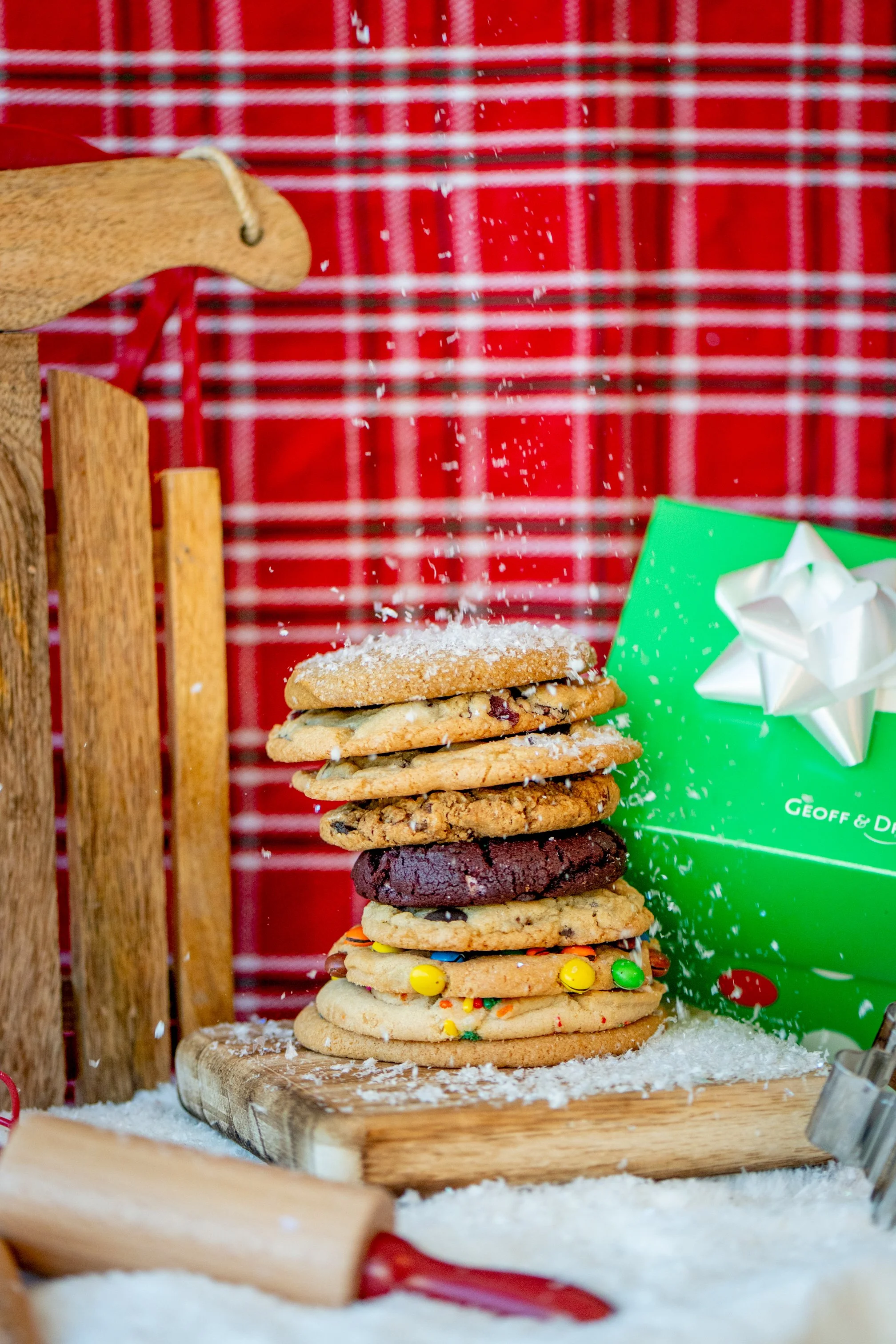 Assorted cookies beside a green holiday gift box with a white bow.