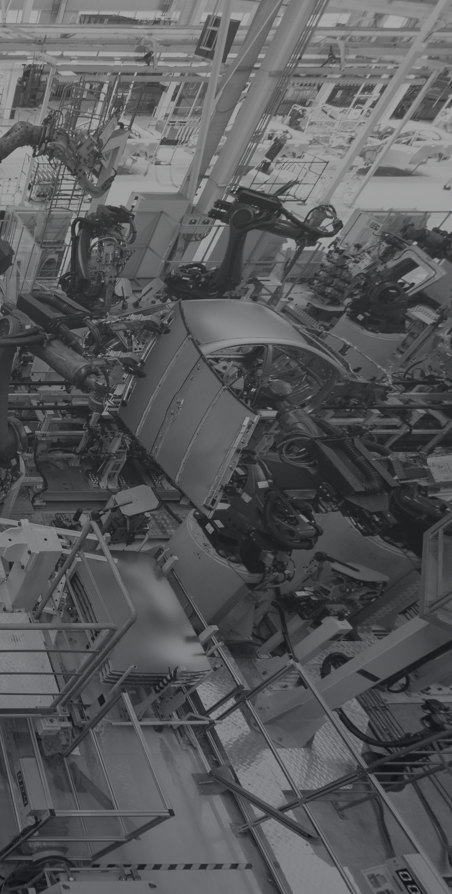 Interior de una línea de ensamblaje de vehículos con robots y maquinaria industrial en un entorno de fábrica.