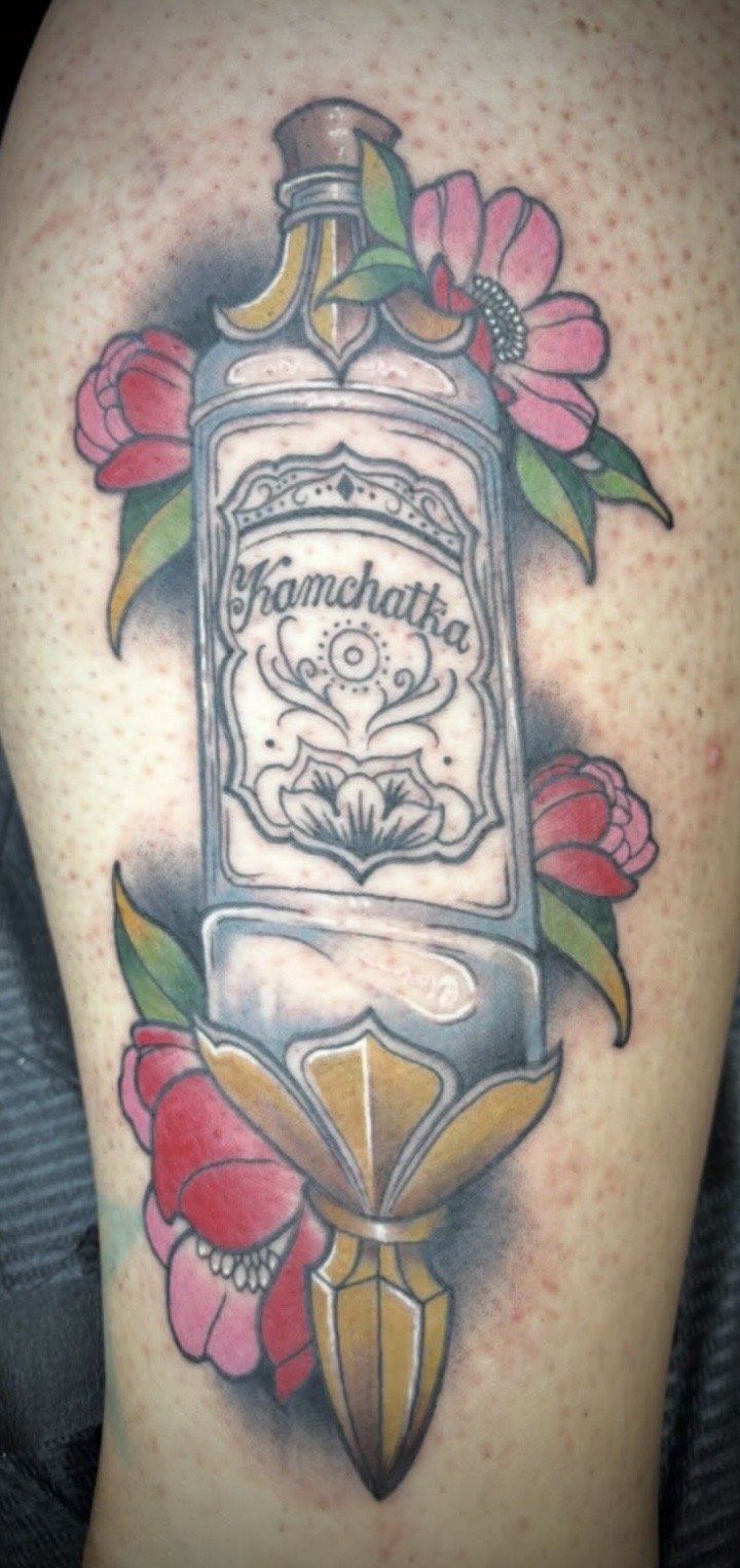 Neo Traditional colorful Kamchatka vodka bottle tattoo on a leg by Altered Tattoo Co