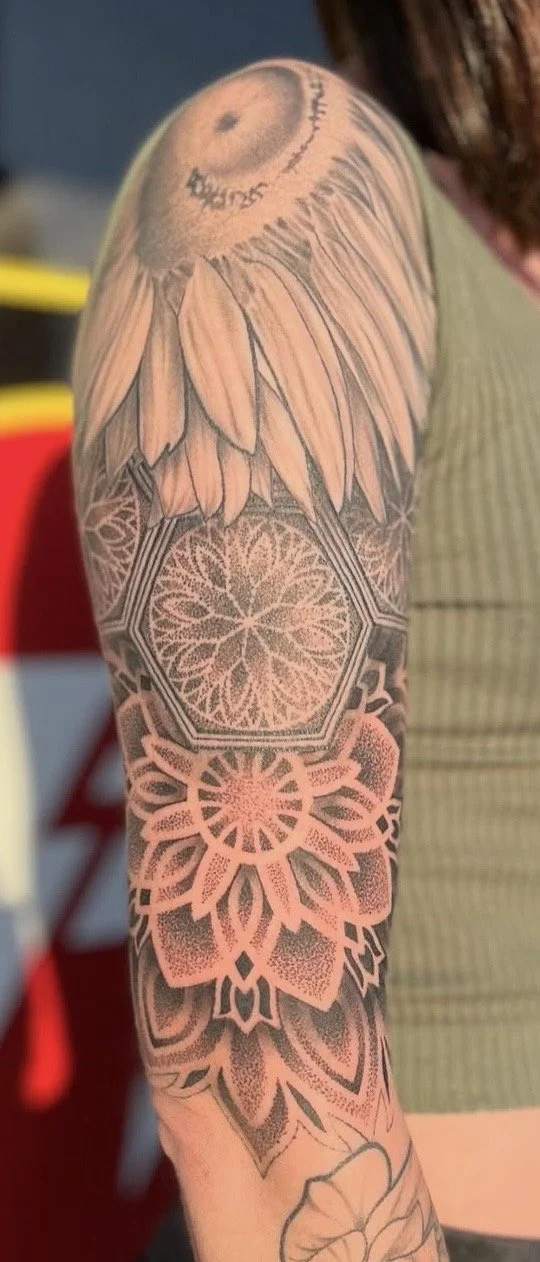 Black and grey floral and geometric arm sleeve tattoo on a woman by Altered Tattoo Co