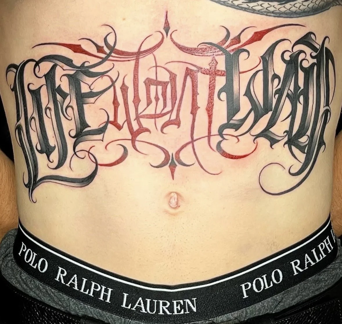 Script tattoo saying "life wont wait" on a stomach by Altered Tattoo Co