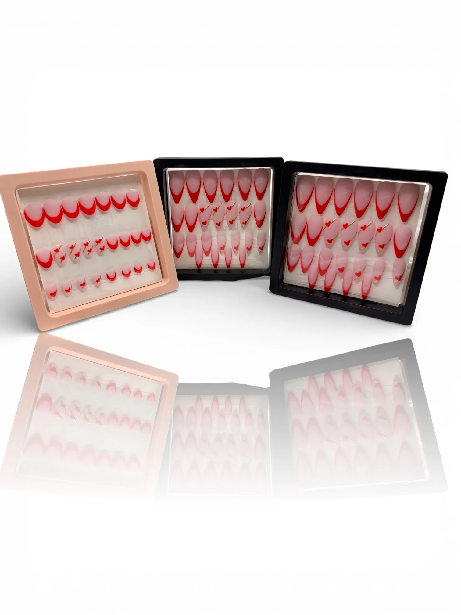 medium Matte stiletto press-on nails with nude pink bases, red V-shaped French tips, and delicate red heart designs.