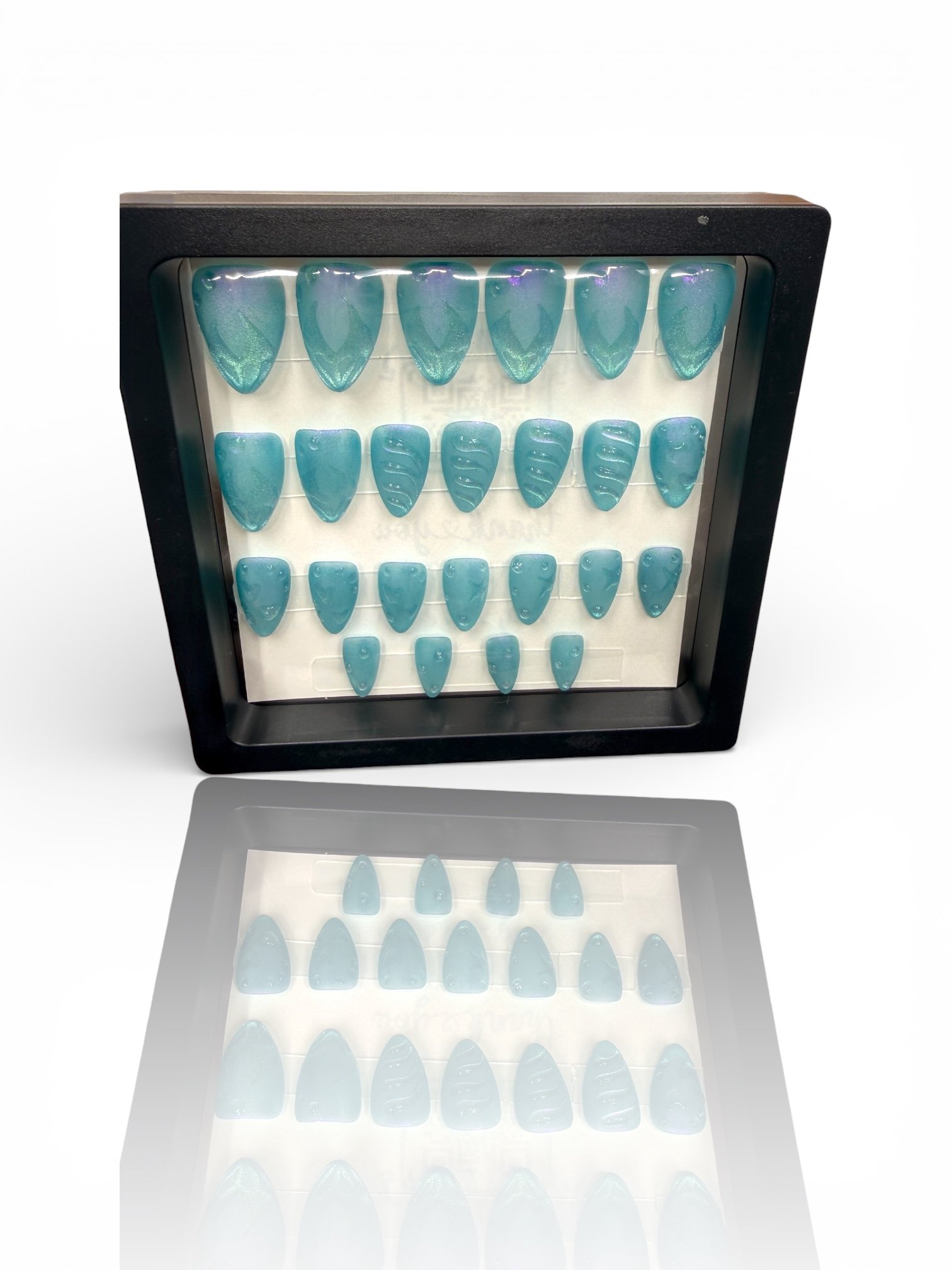 short Shimmering ocean blue almond-shaped press-on nails with mermaid-inspired scales, textured wave details, and an iridescent finish.