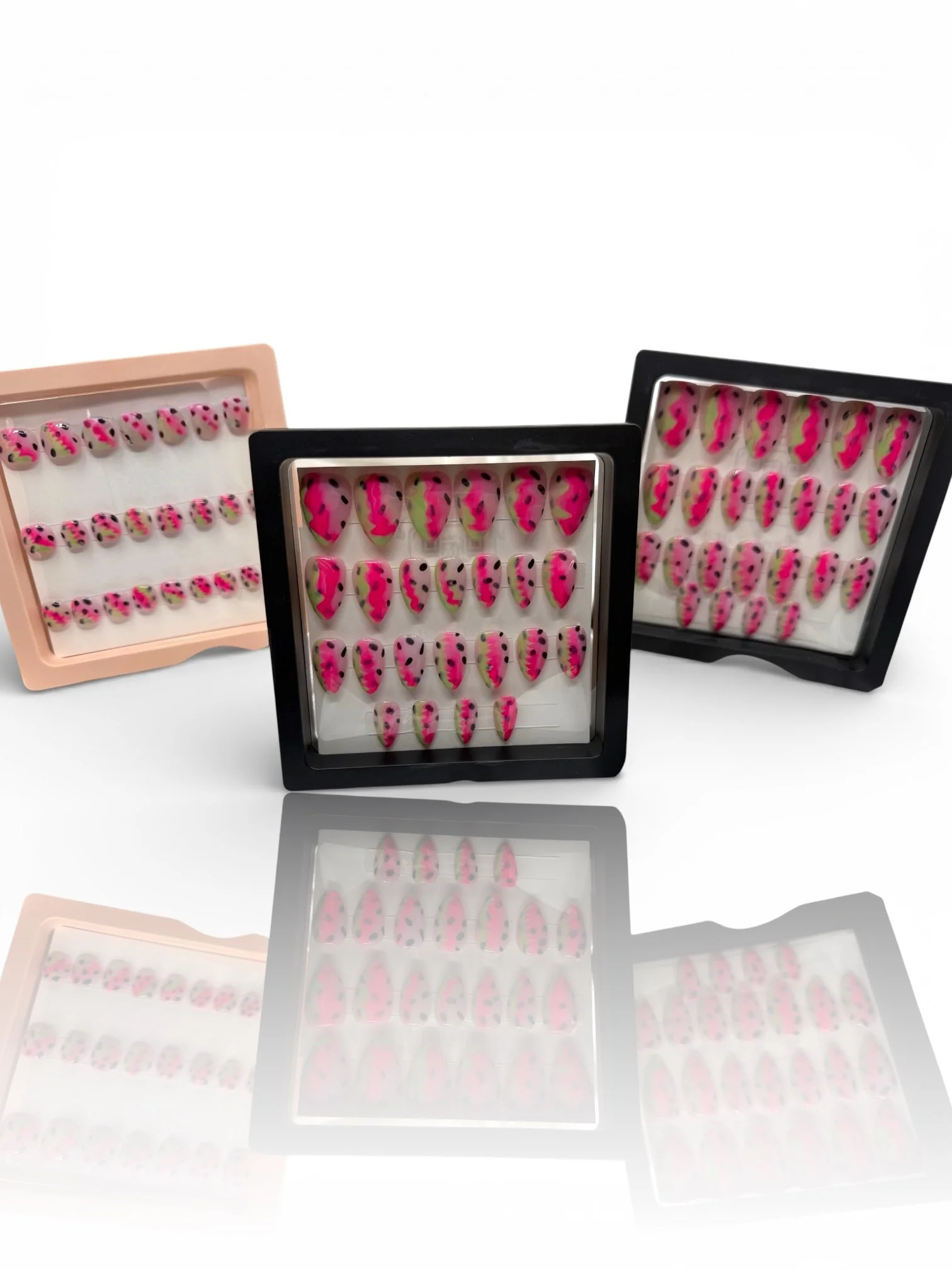 Colorful watermelon almond-shaped press-on nails with bright pink fruit designs, green rinds, and black seeds.