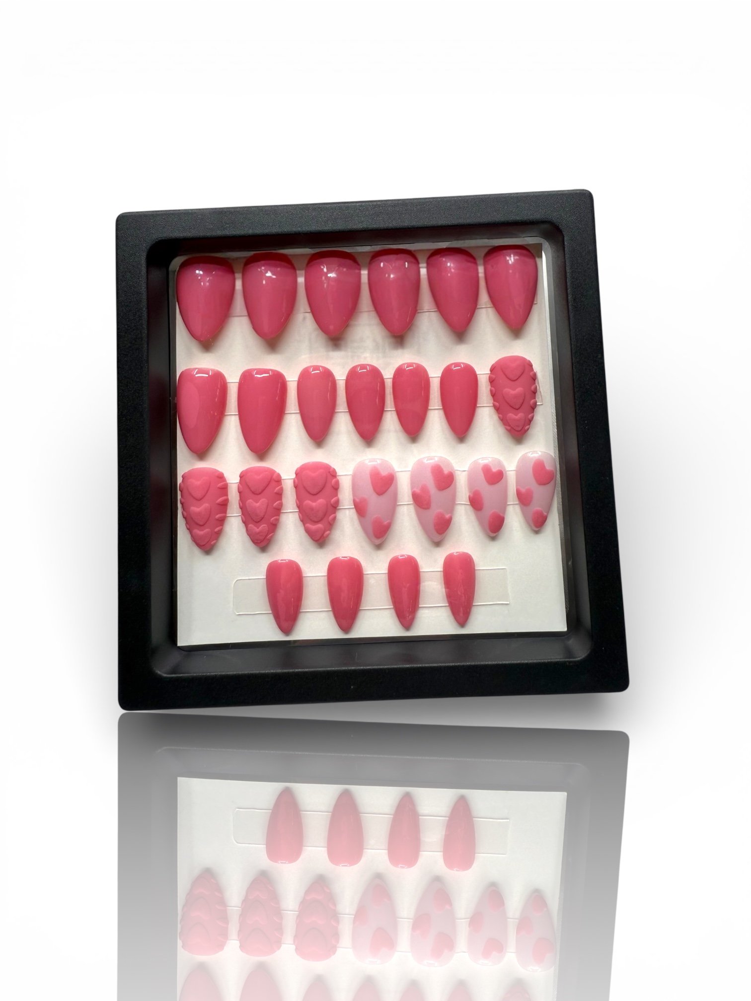 Pink almond-shaped press-on nails with 3D sweater-knit heart designs, raised textures, and pink heart accents.