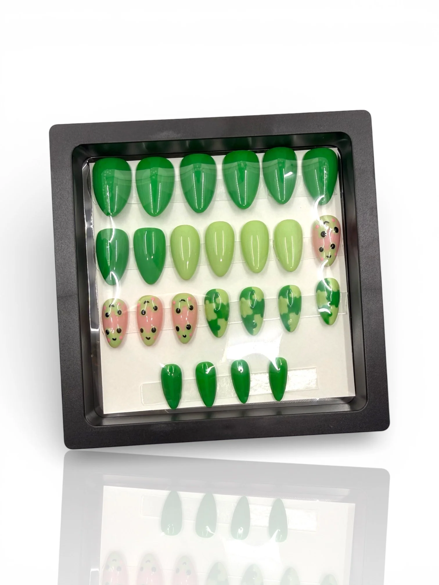 long Green almond-shaped press-on nails with cute pink frog faces, lily pad designs, and glossy light and dark green accents.