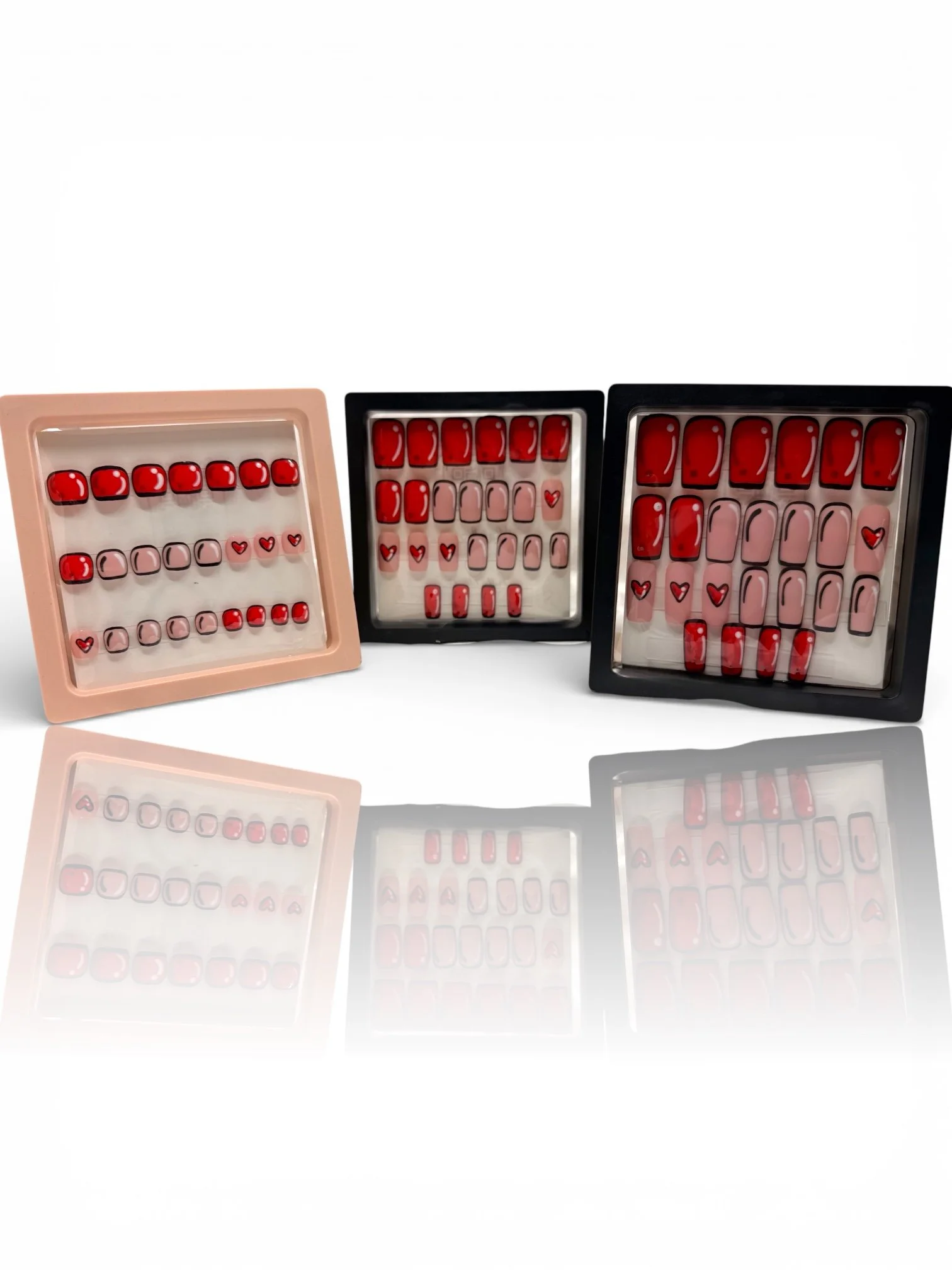 short matte red and pink square press-on nails with black outlines, white shine accents, and cute red heart designs.