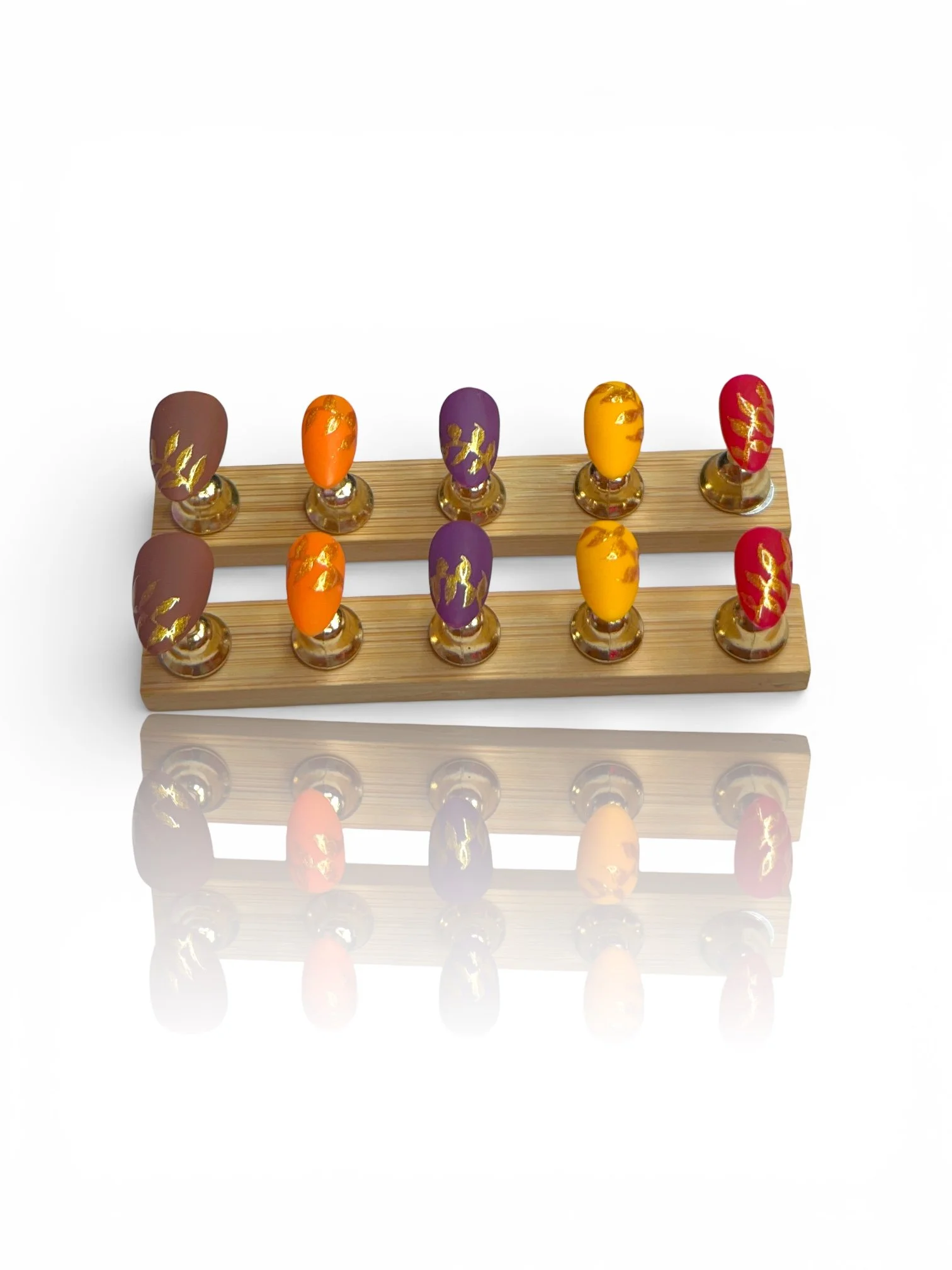 Almond press-on nails with autumn colors and metallic gold leaf designs.