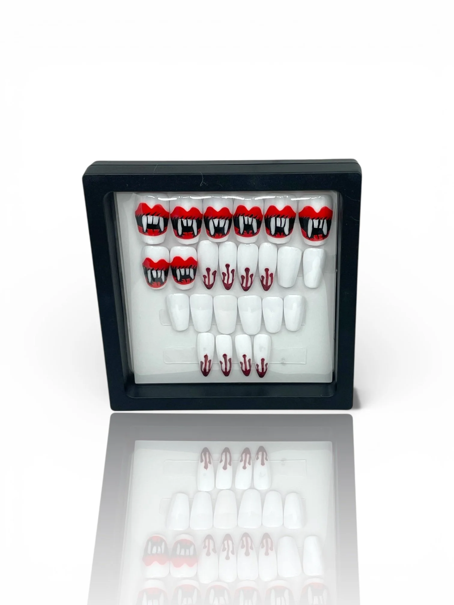 Halloween vampire press-on nails in square and stiletto shapes with red fangs, black details, and dripping blood nail art.