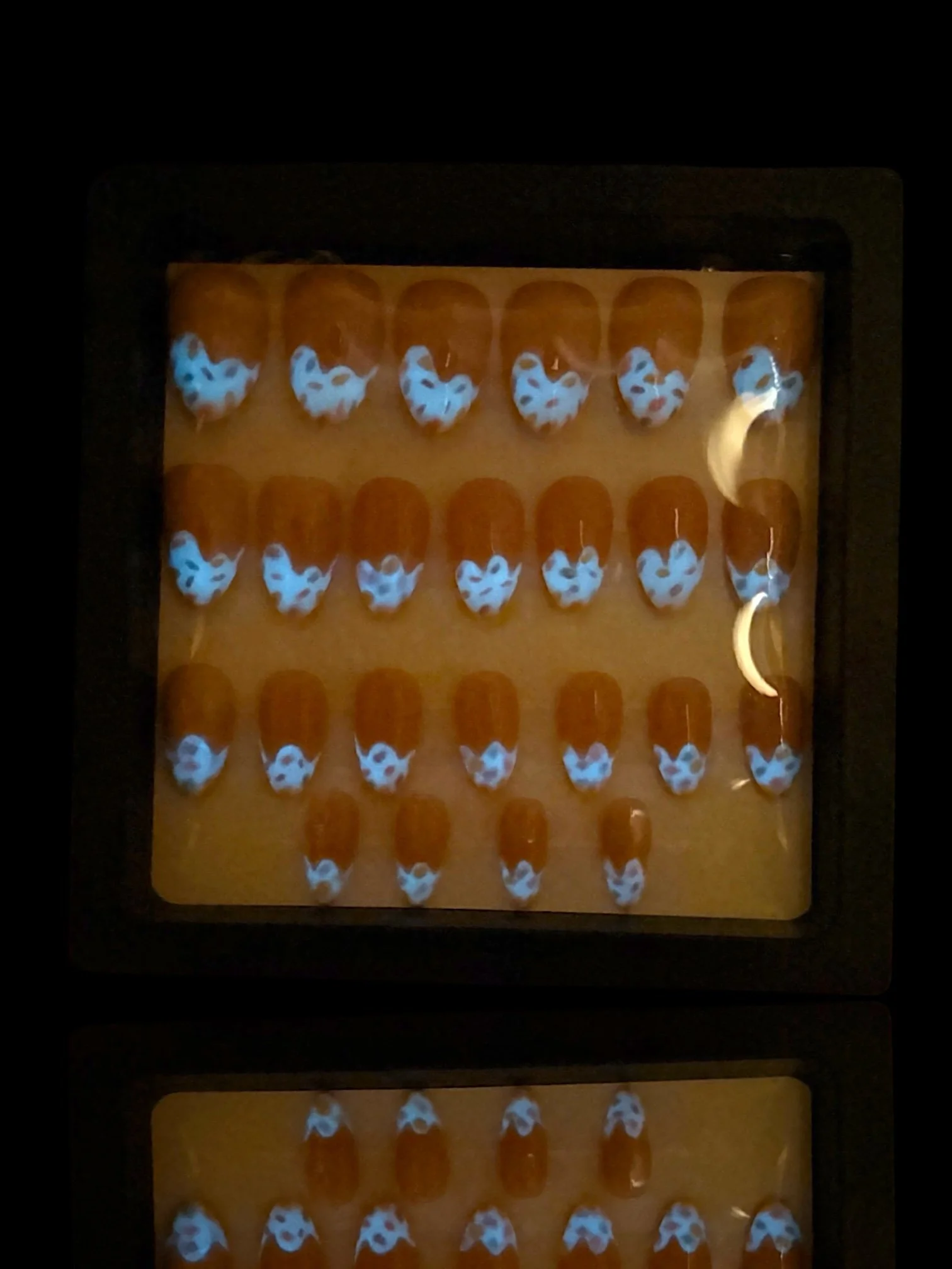 glowing Glow-in-the-dark almond press-on nails with glossy pink bases and colorful pastel ice cream-inspired French tips.