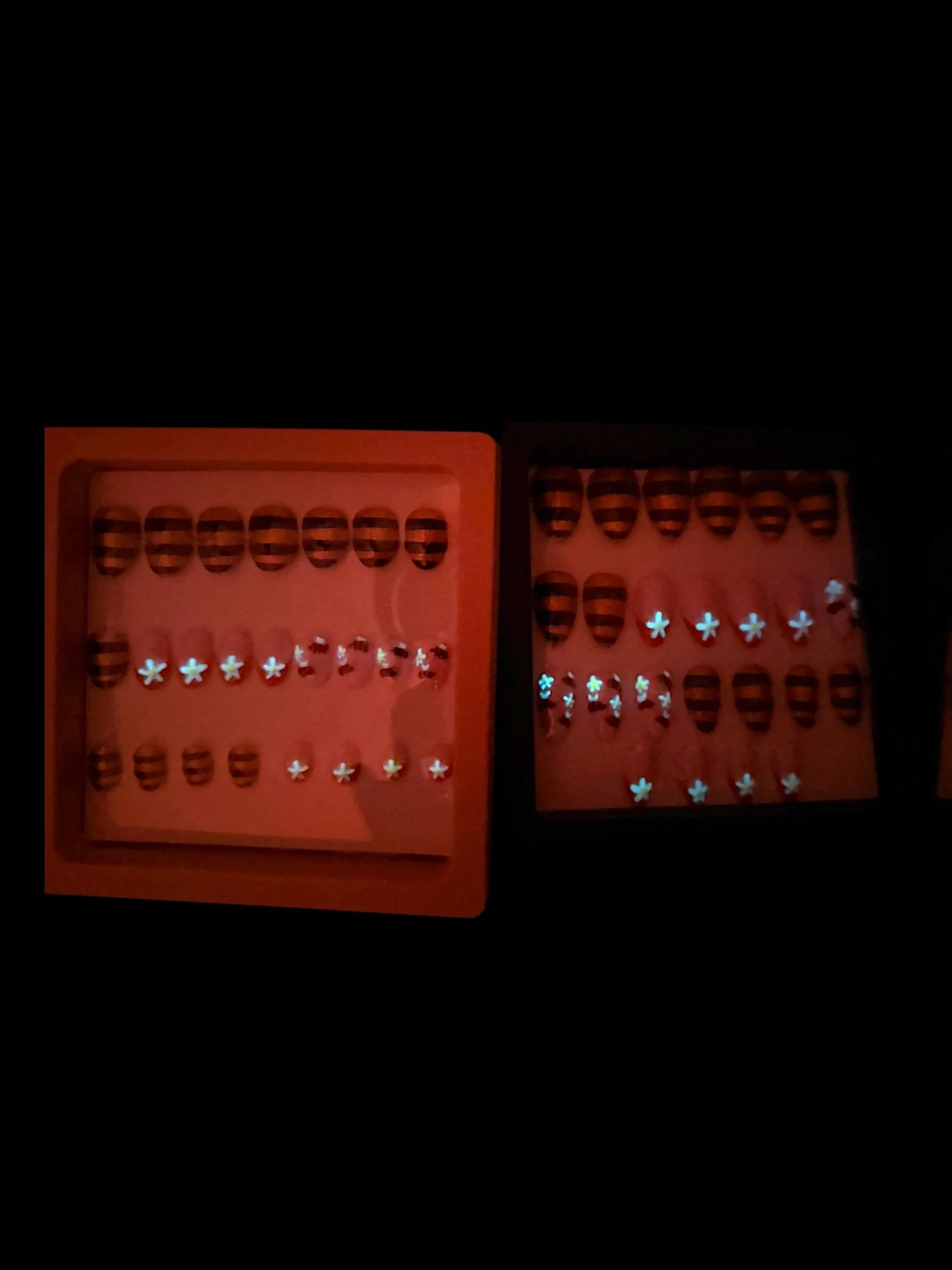 glowing Glow-in-the-dark almond press-on nails with glittery orange and black bee stripes, pink bases, and cute bumblebee designs.