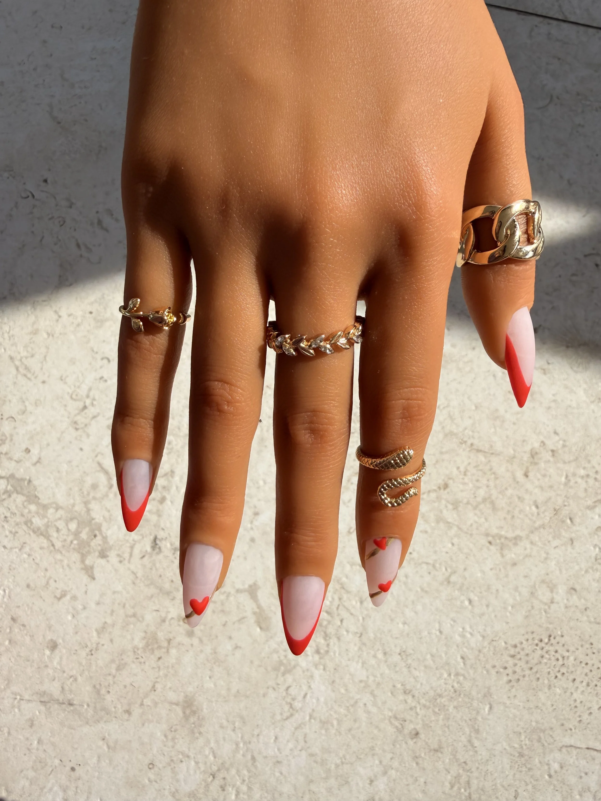 Hand with rings and decorated nails, fingers spread out against a light background.