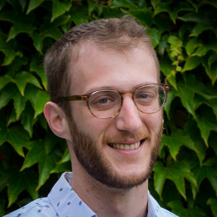 Ari Goodman, LCSW, smiling outdoors in natural light with green leaves behind him