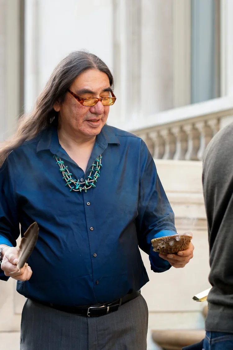 George Stonefish smudging attendees with tobacco and sage prior to entering the Duke House.