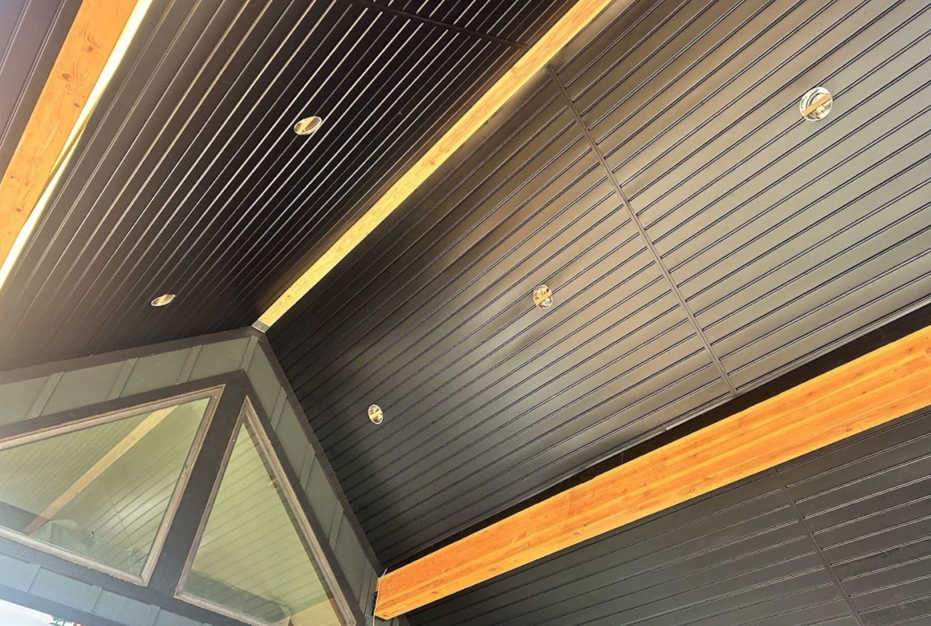 Ceiling with dark wood paneling, built-in lighting, and glass windows.