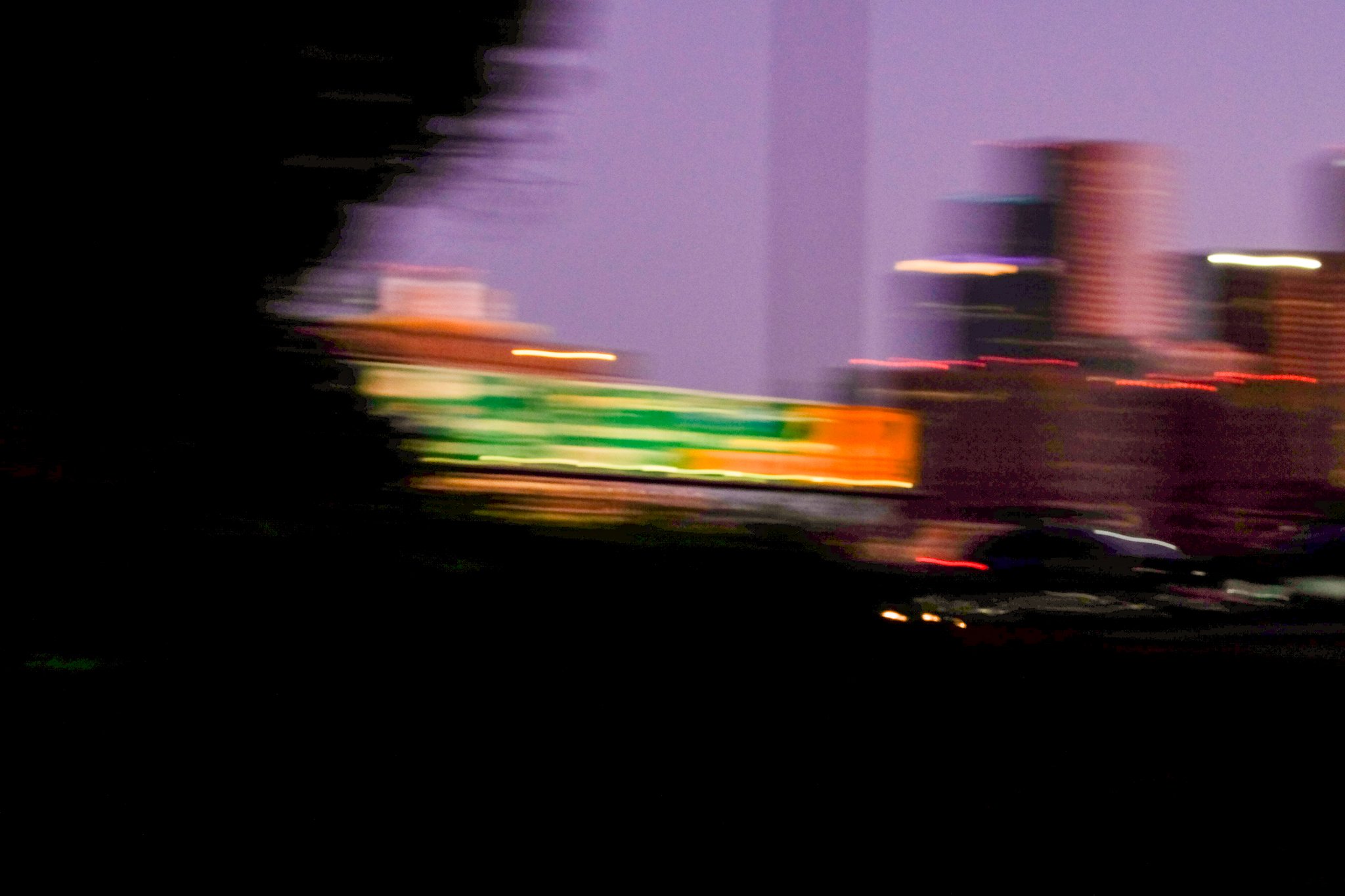 Blurred cityscape at night with streaks of lights and purple sky.