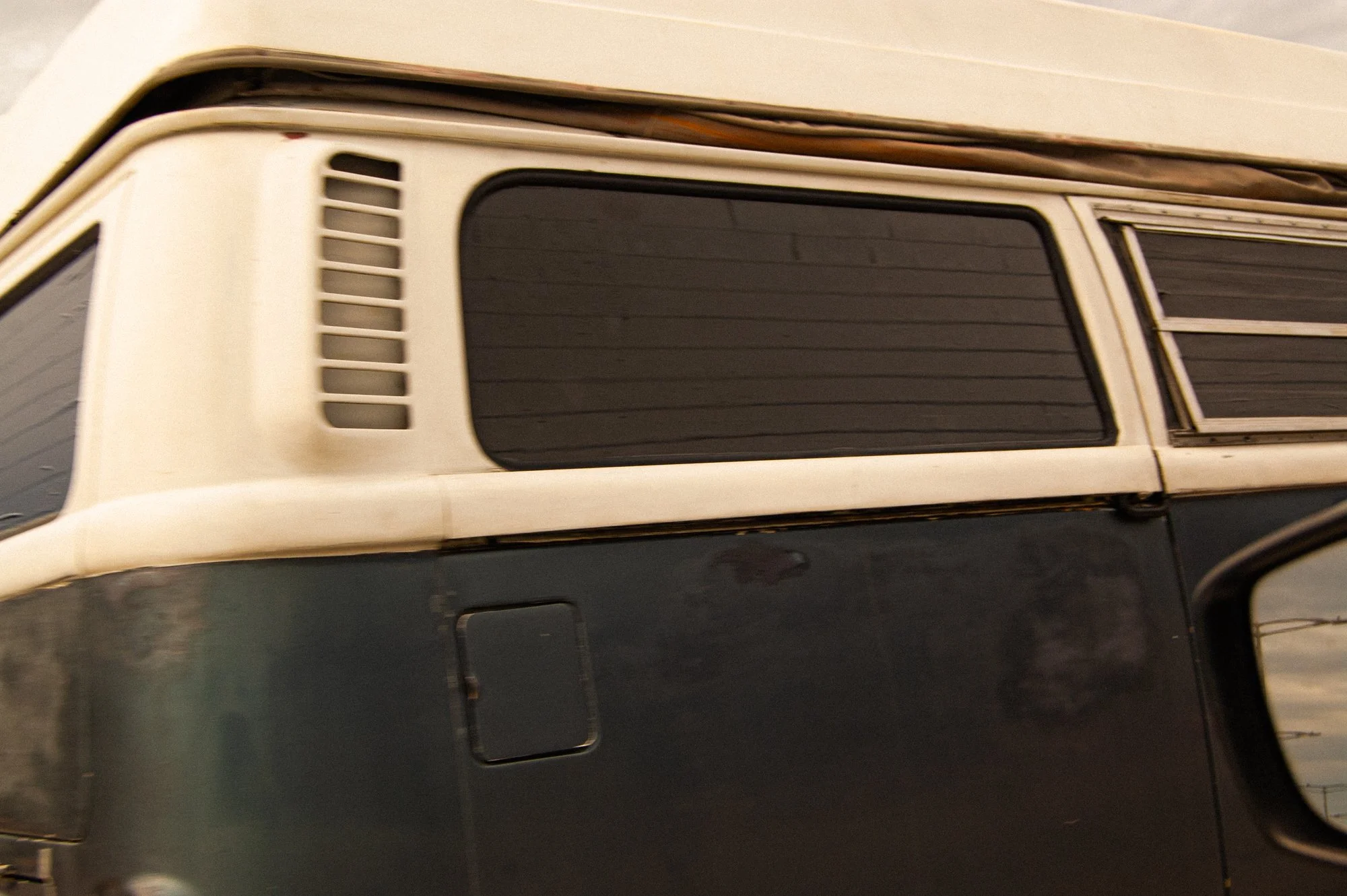 Close-up of a vintage off-white car with a roof rack holding cardboard boxes, parked on a dark surface.