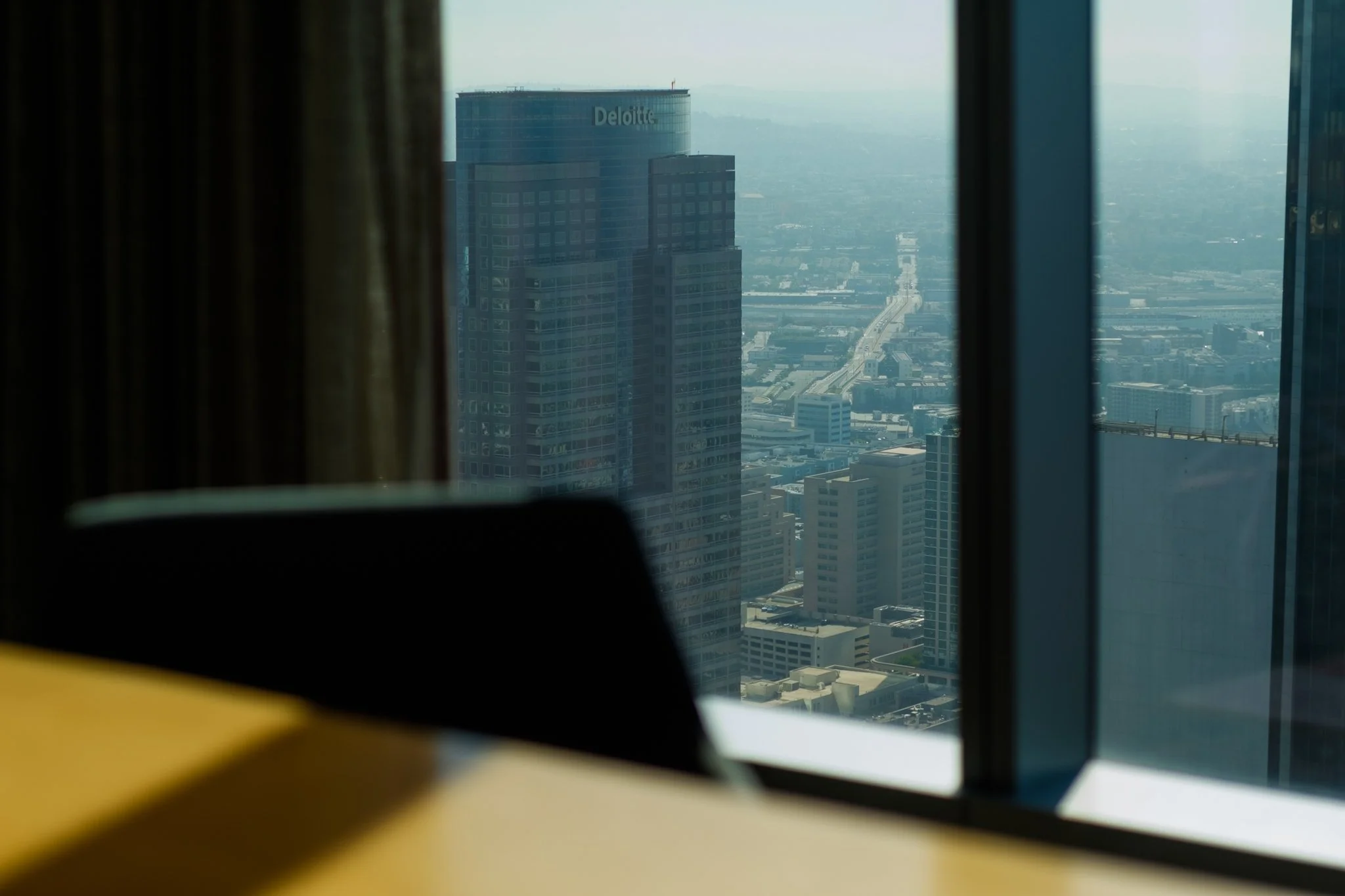 View of a city skyline through a window, with tall buildings and streets visible in the background.