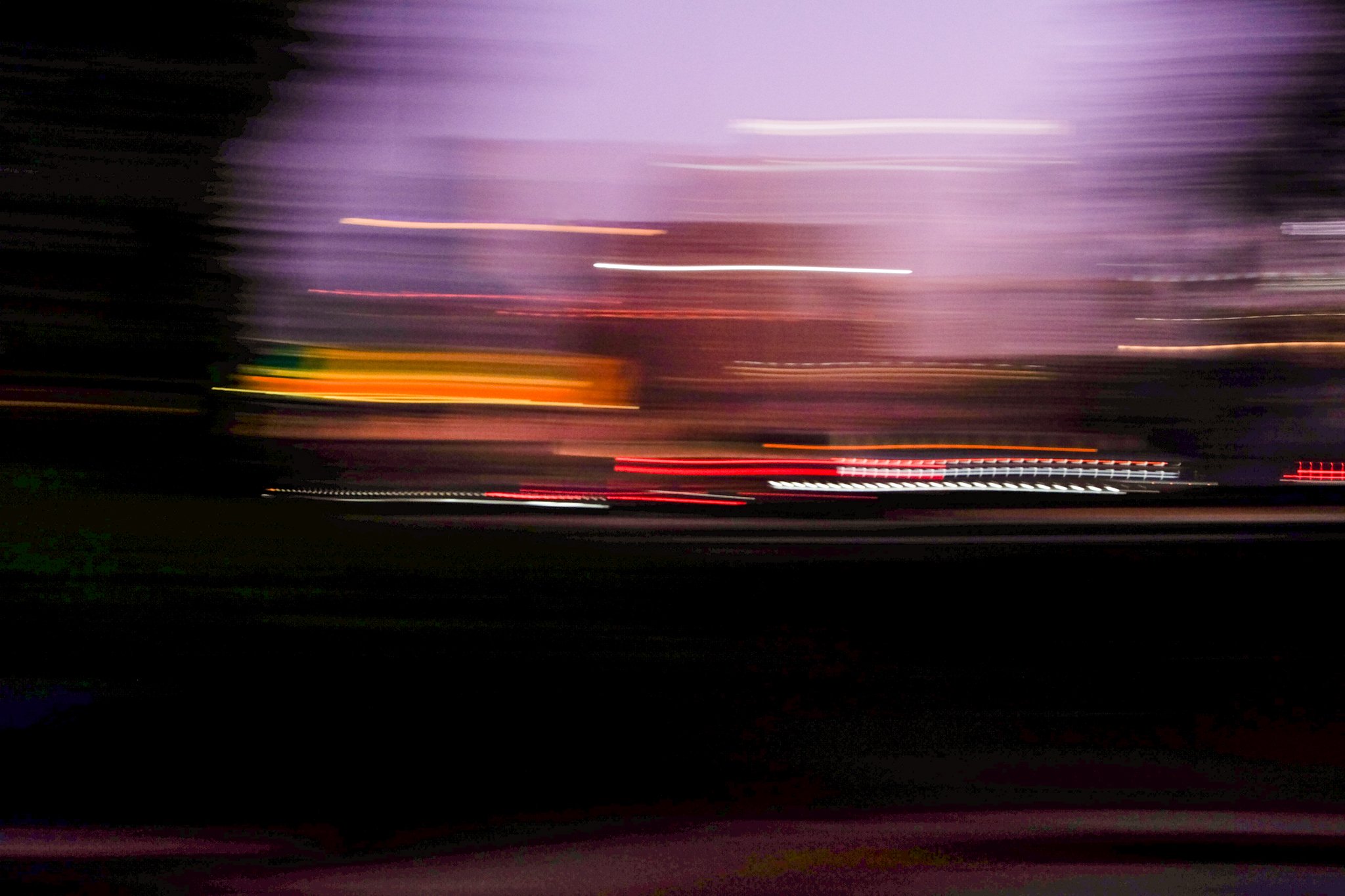 Blurred motion photo of city lights at night with purple sky.